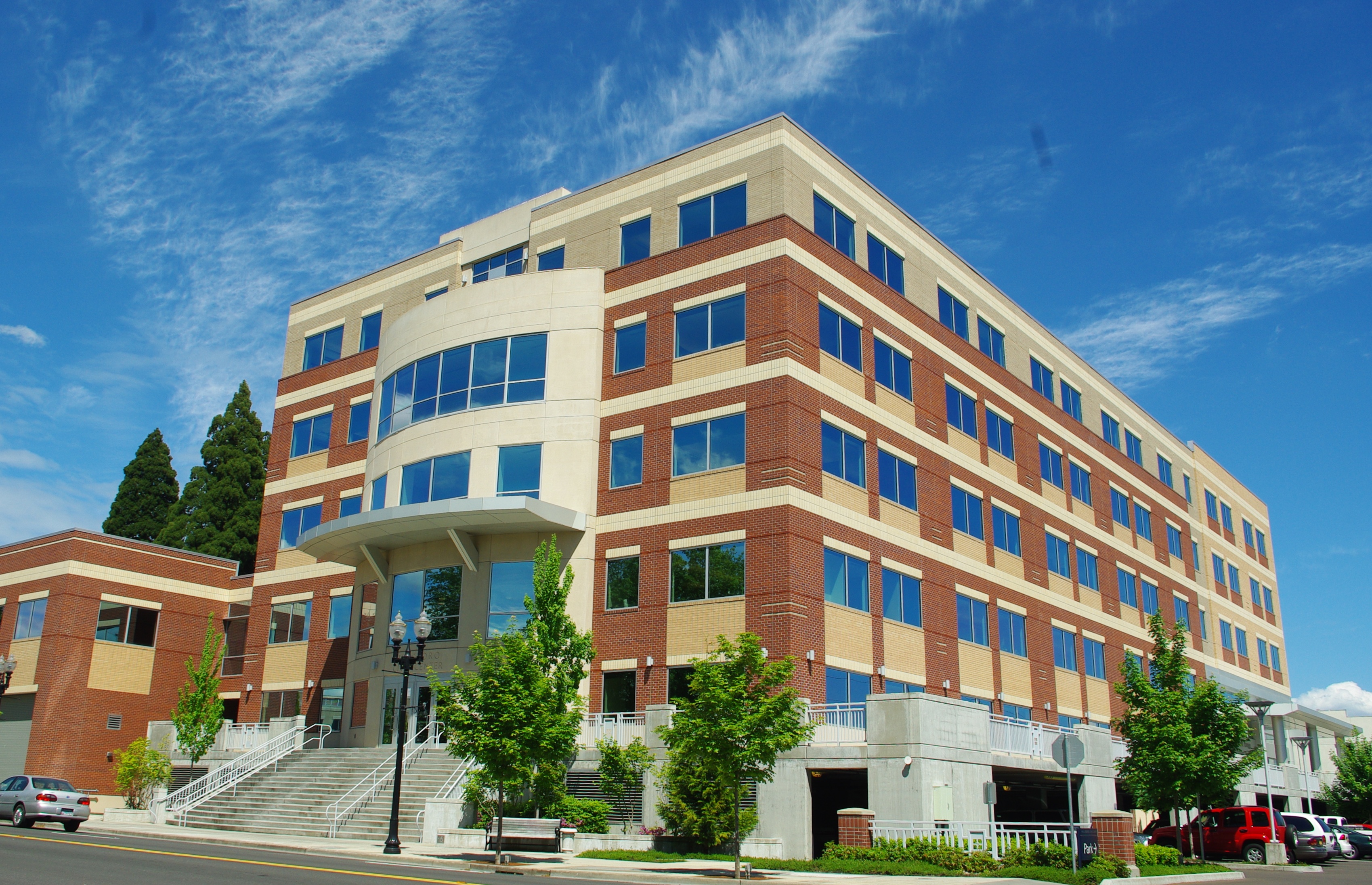 Multi-story brick and beige government building with blue-tinted windows and exterior stairs.