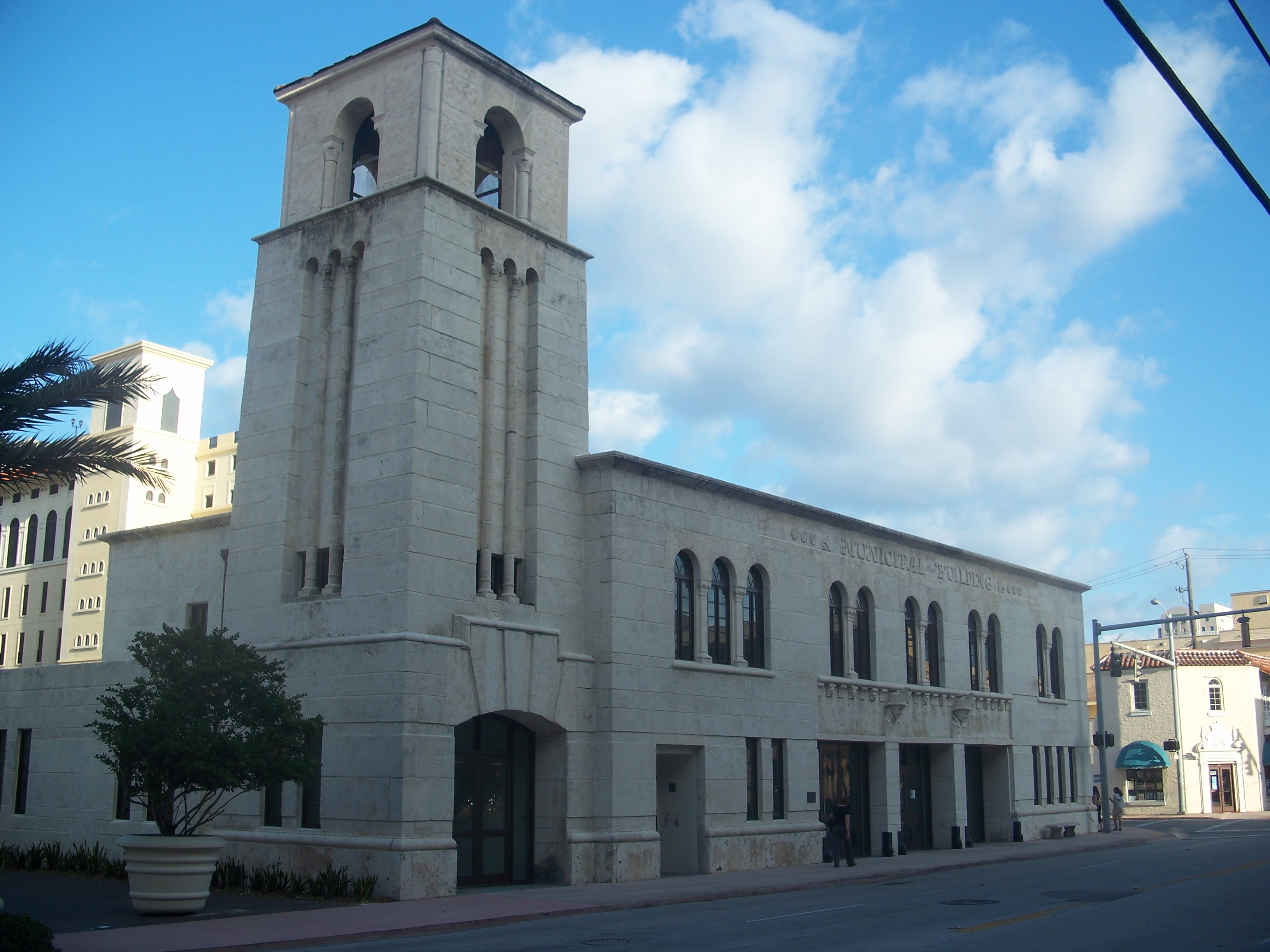 Large stone building with a tall bell tower on a Coral Gables street.