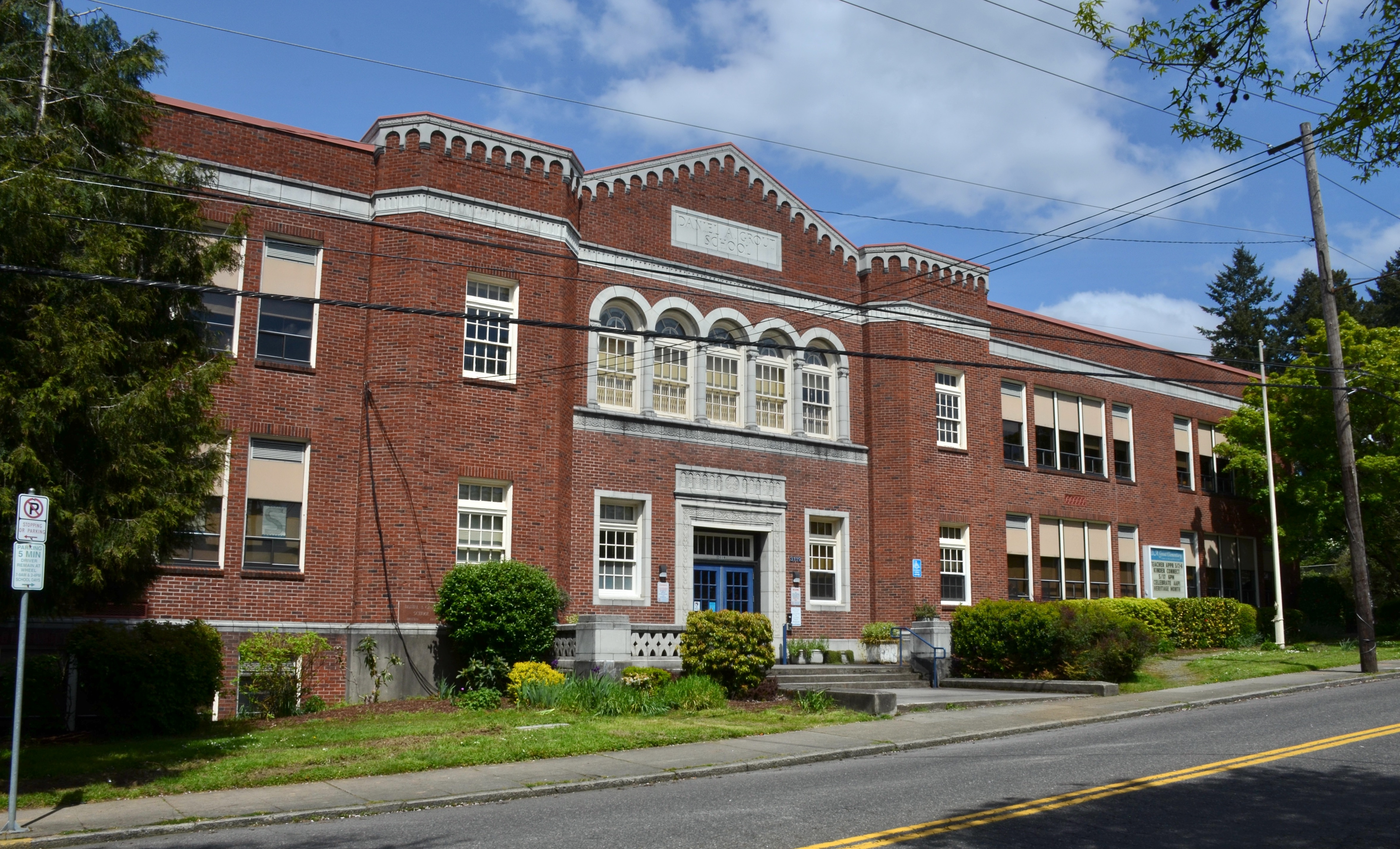Two-story red brick school building with arched windows and a central entrance.