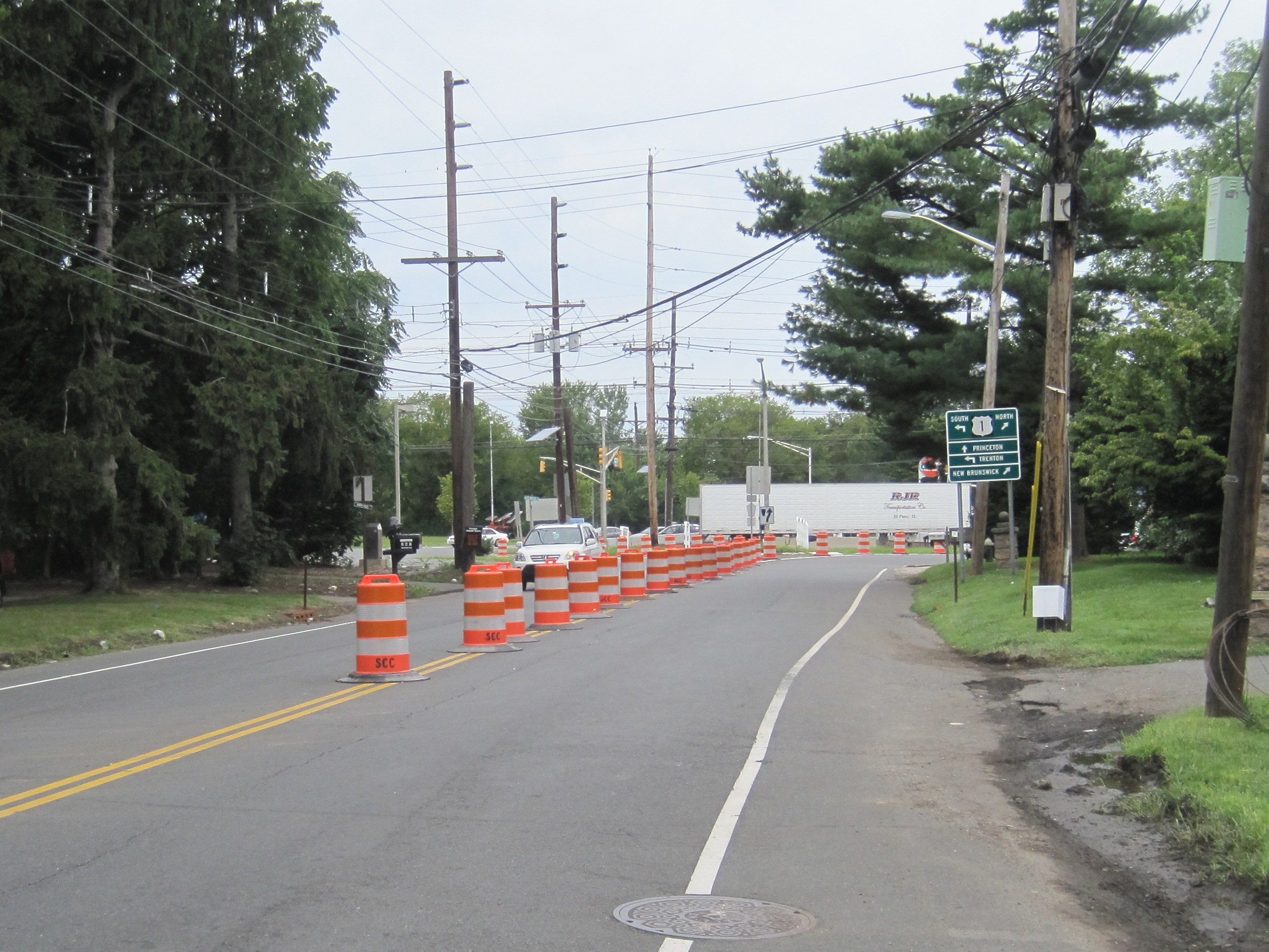 Road lined with orange construction bollards under a clear sky.