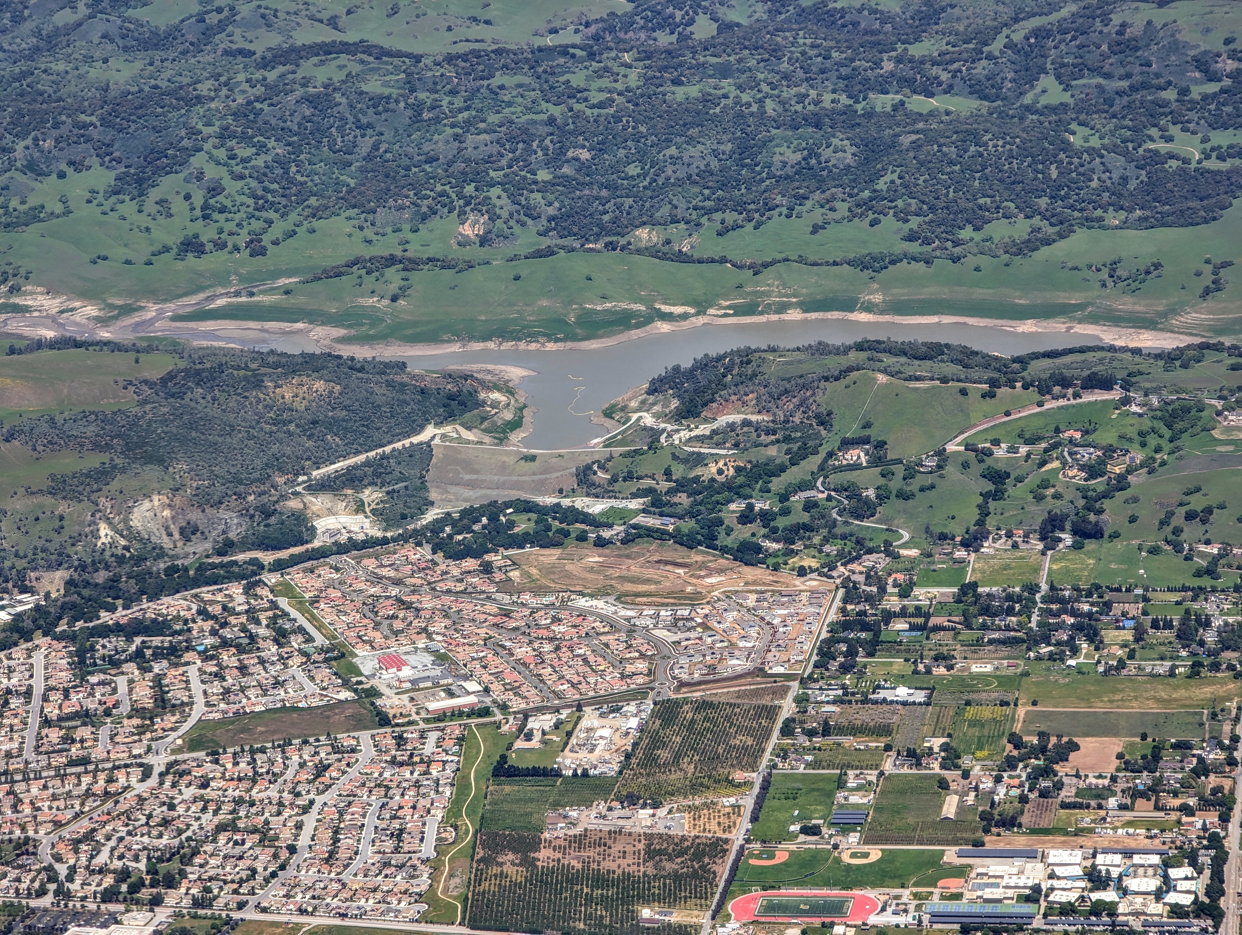 Aerial view of a reservoir at low water level surrounded by dry hills.