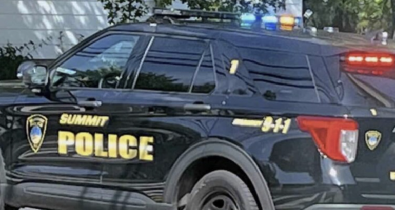 A black Summit Police SUV with emergency lights on and gold lettering on the side.