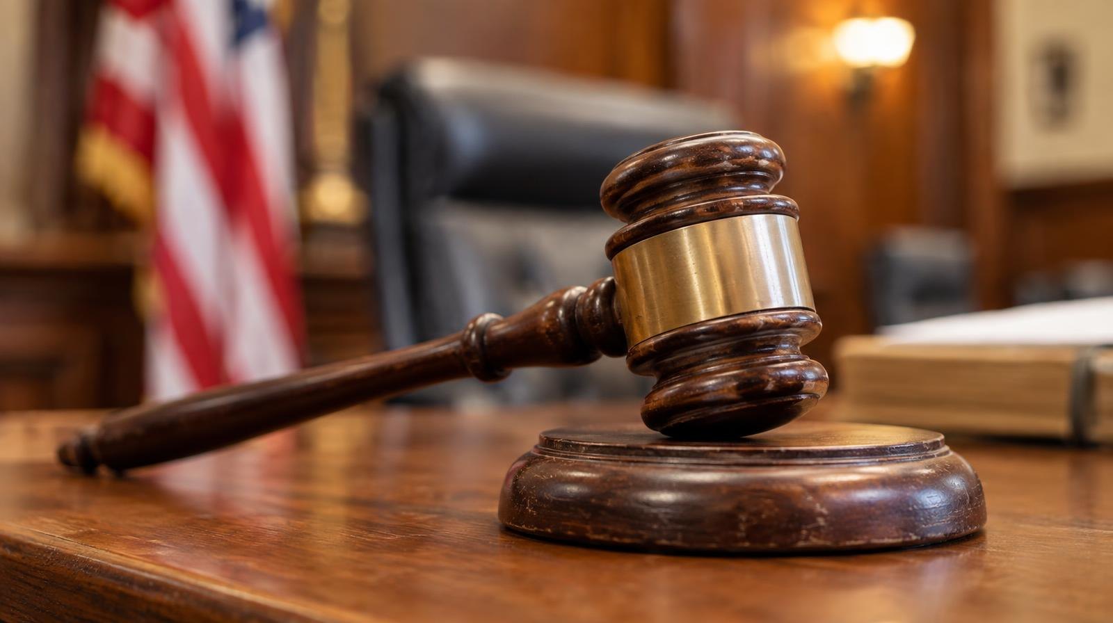 Wooden gavel resting on its sound block on a courtroom bench.