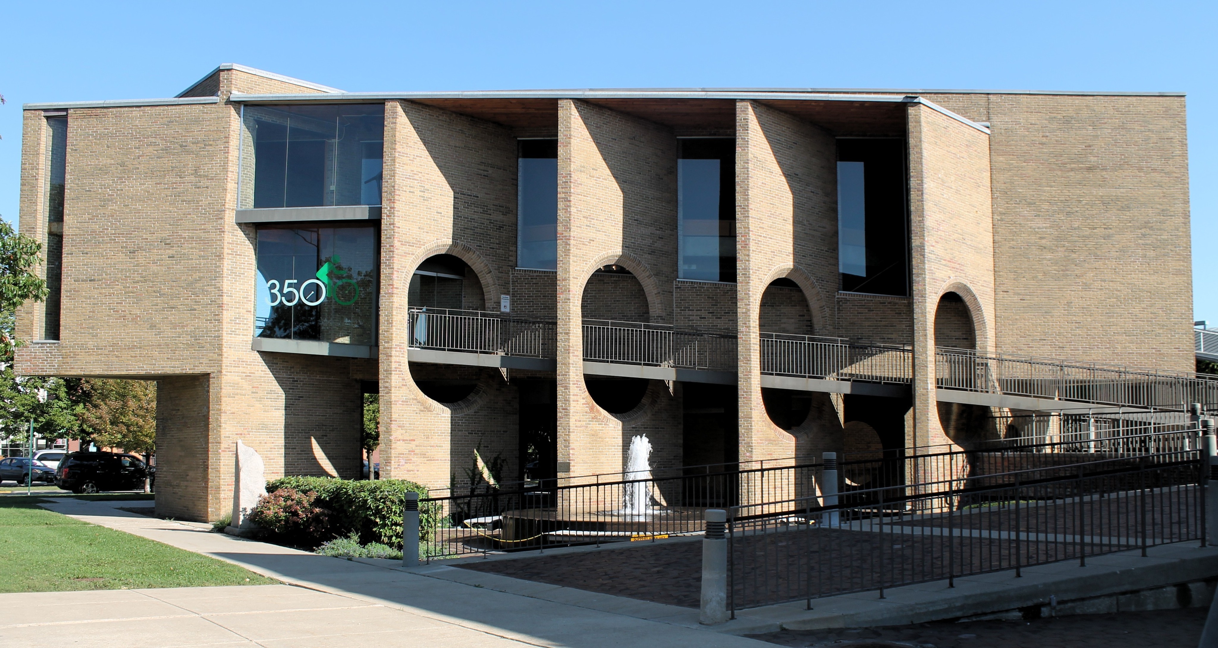 Two-story modernist brick building with arched openings and second-floor balconies.
