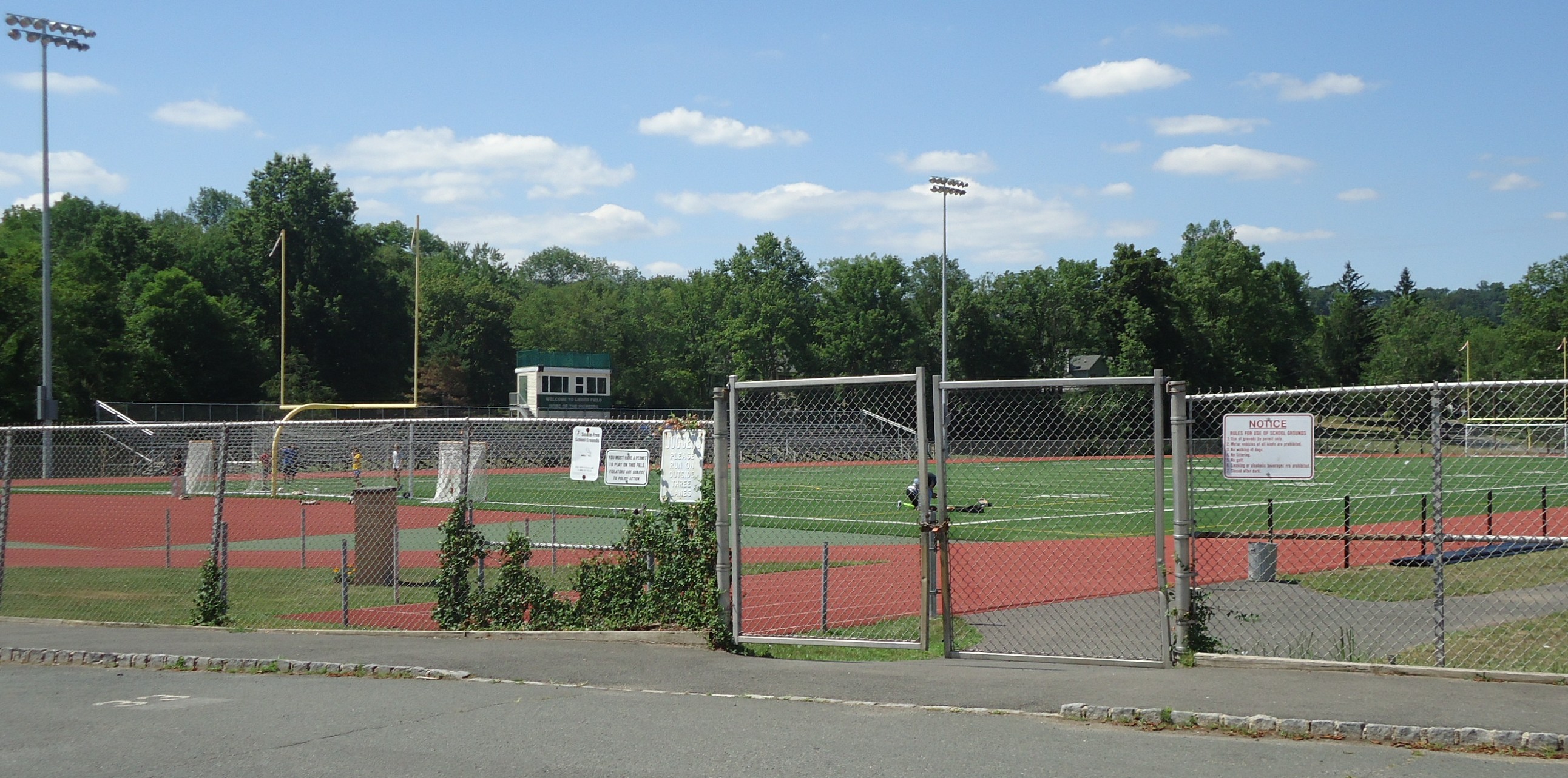 Aerial view of a fenced high school football field with a red running track.