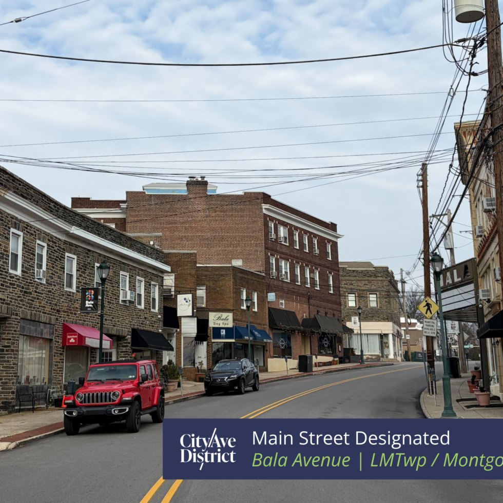 Stone and brick commercial buildings line a two-lane street with overhead utility lines.
