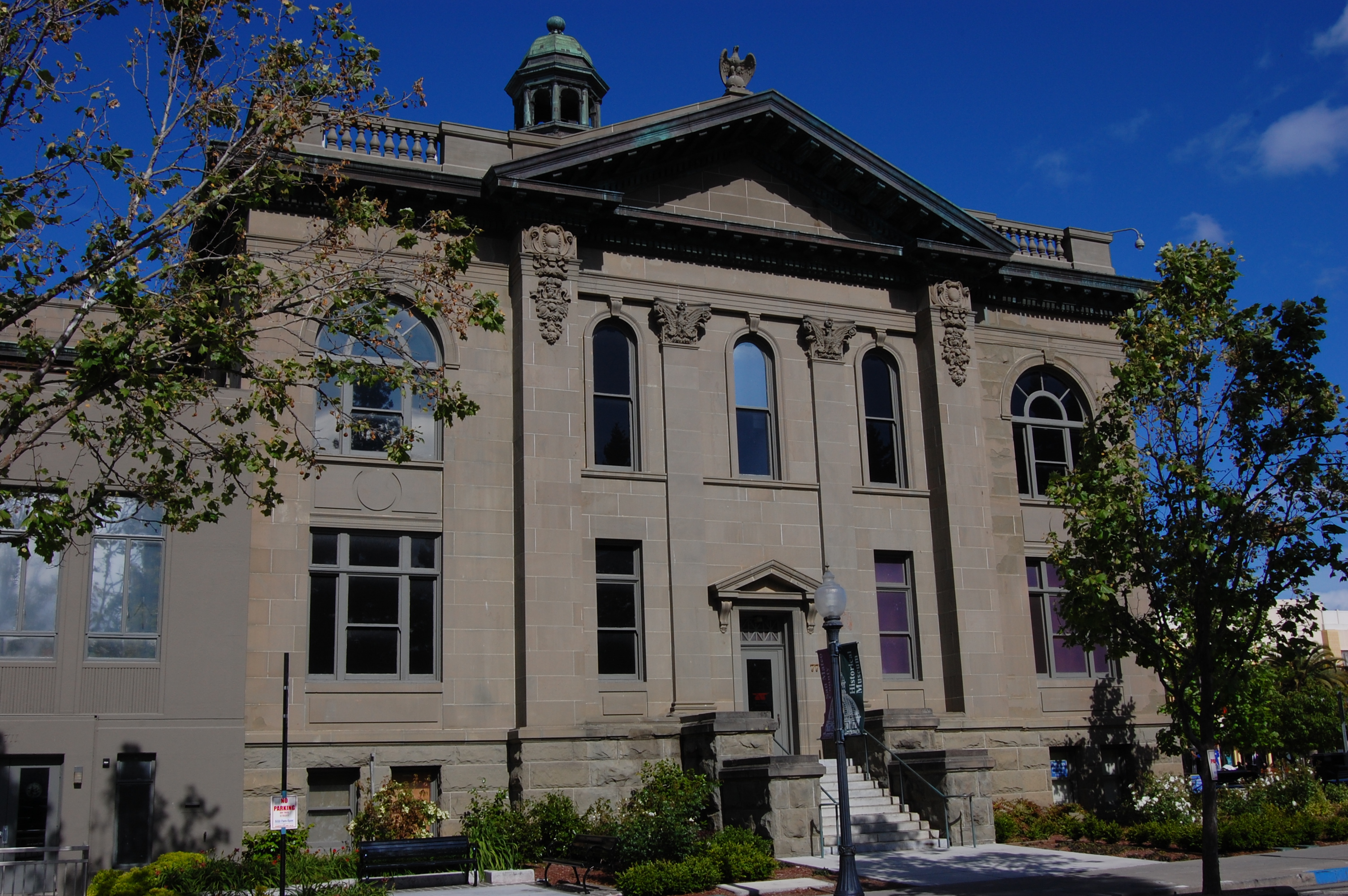 Neoclassical stone courthouse building with arched windows and a copper-green domed cupola.