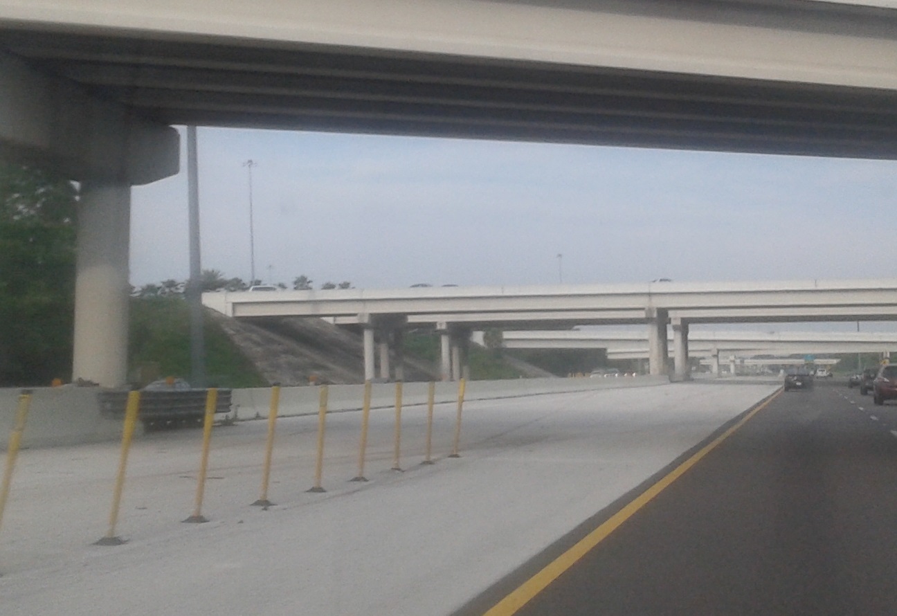Multi-lane highway interchange with concrete barriers and elevated bridge structures.
