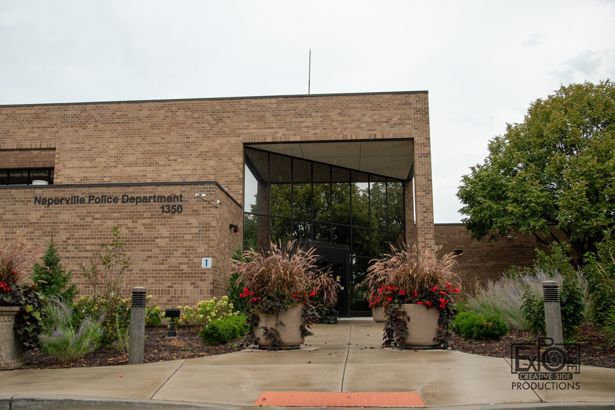 Brick police department building with glass entrance canopy and landscaped planters