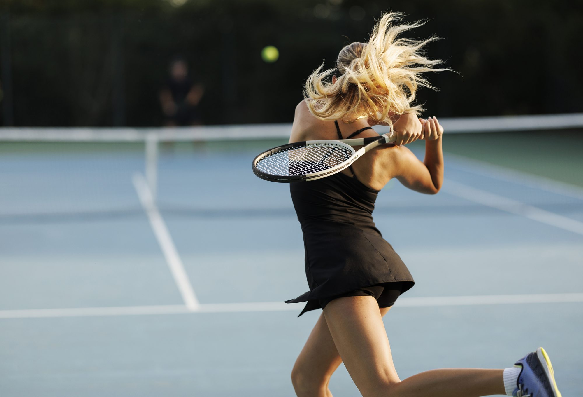 Young female tennis player hitting the ball.