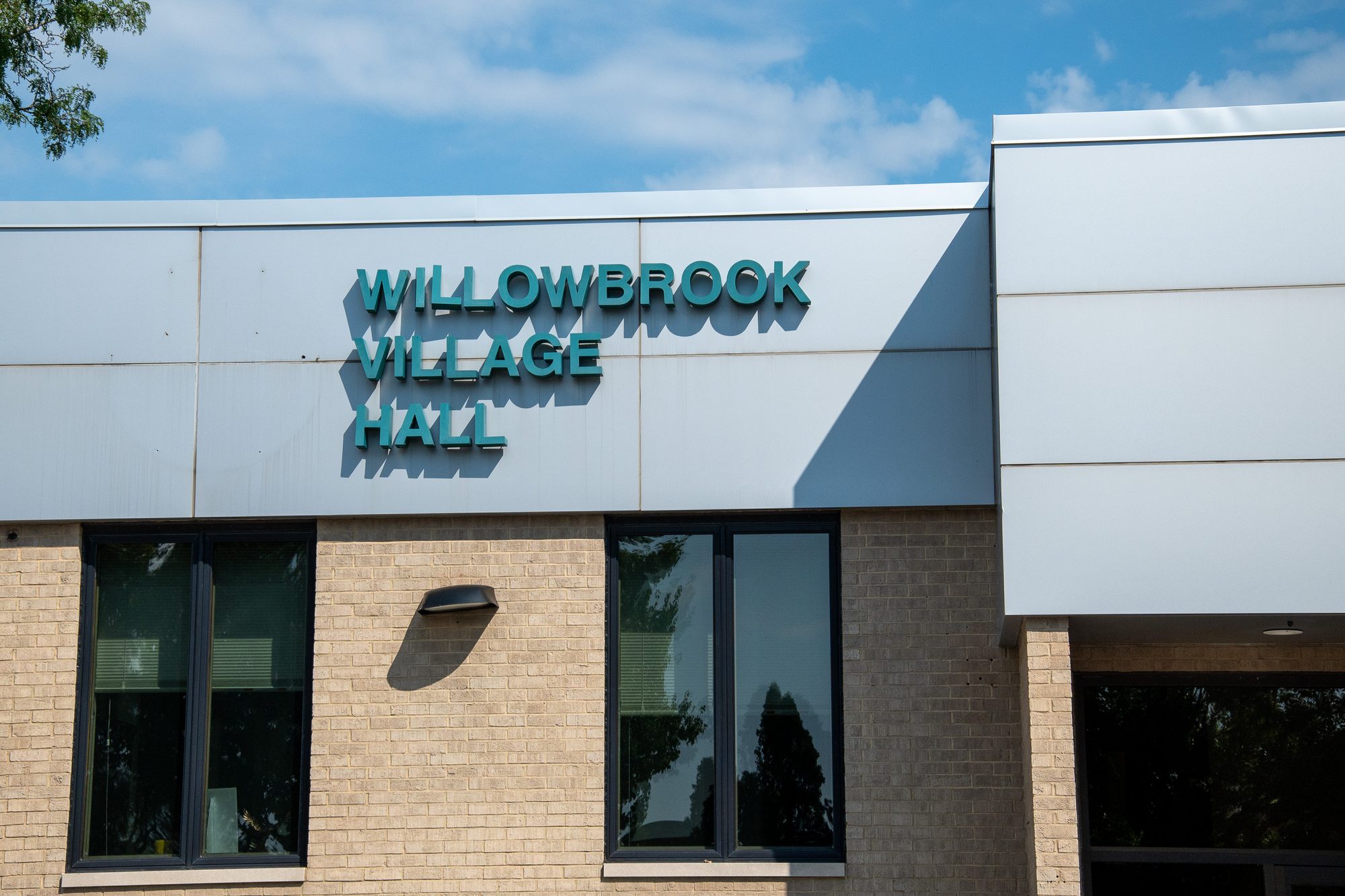 Exterior of a modern brick building with teal lettering reading Willowbrook Village Hall