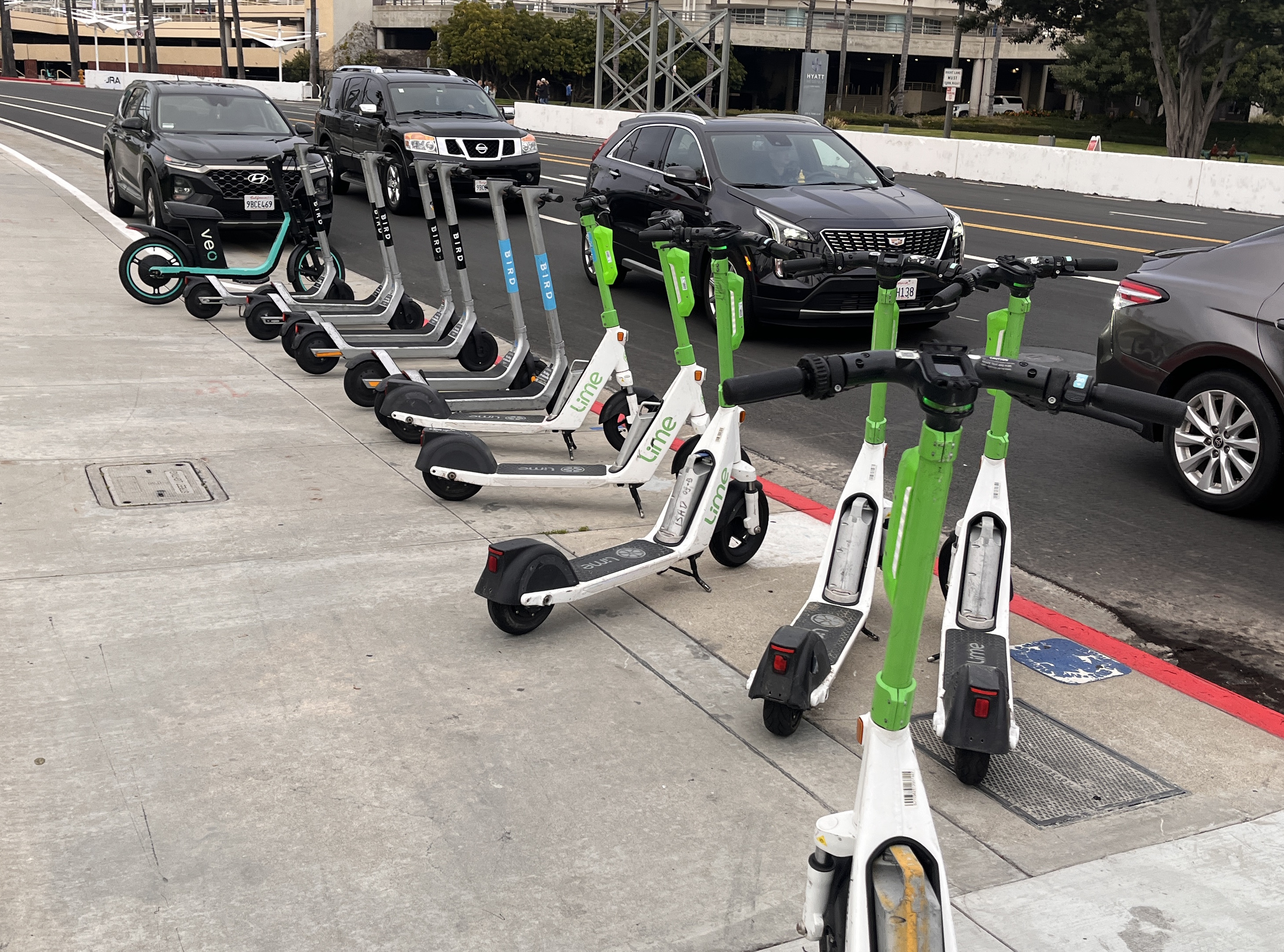 Multiple Lime electric scooters parked in a row on a sidewalk.