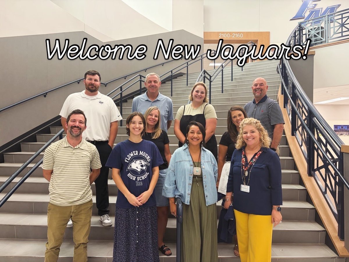 Group of adults posing on an interior school staircase under a 'Welcome New Jaguars!' banner.