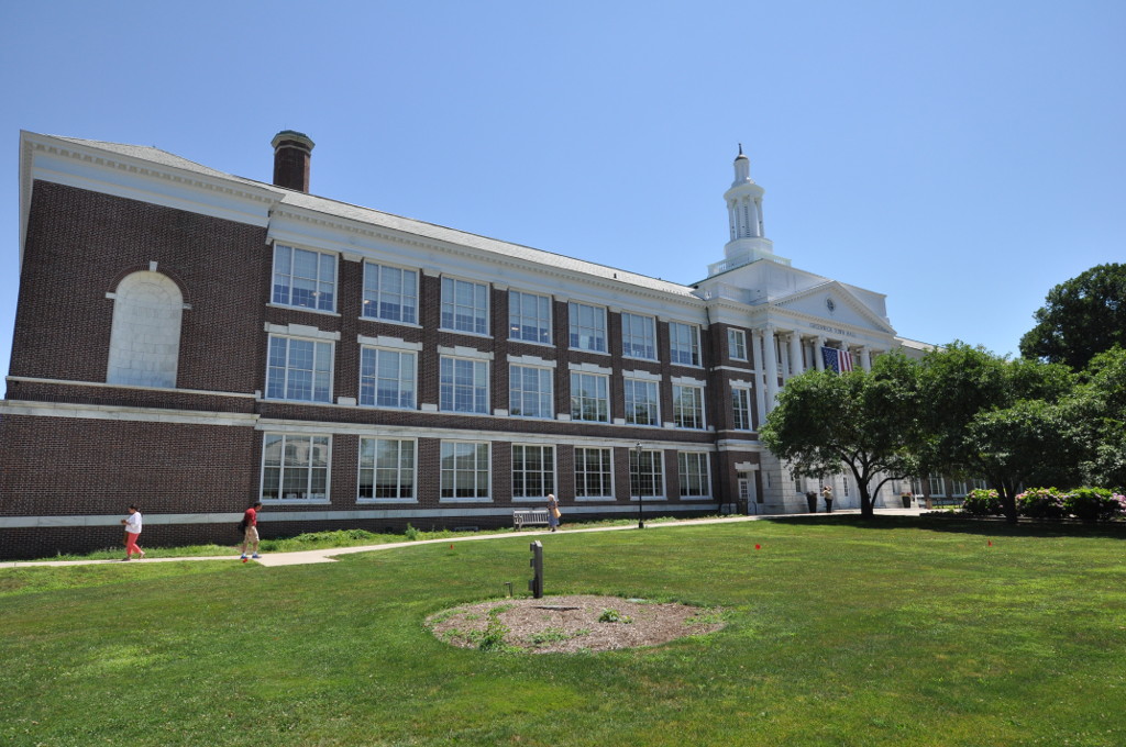Red-brick town hall building with white colonial portico and cupola on a sunny day.