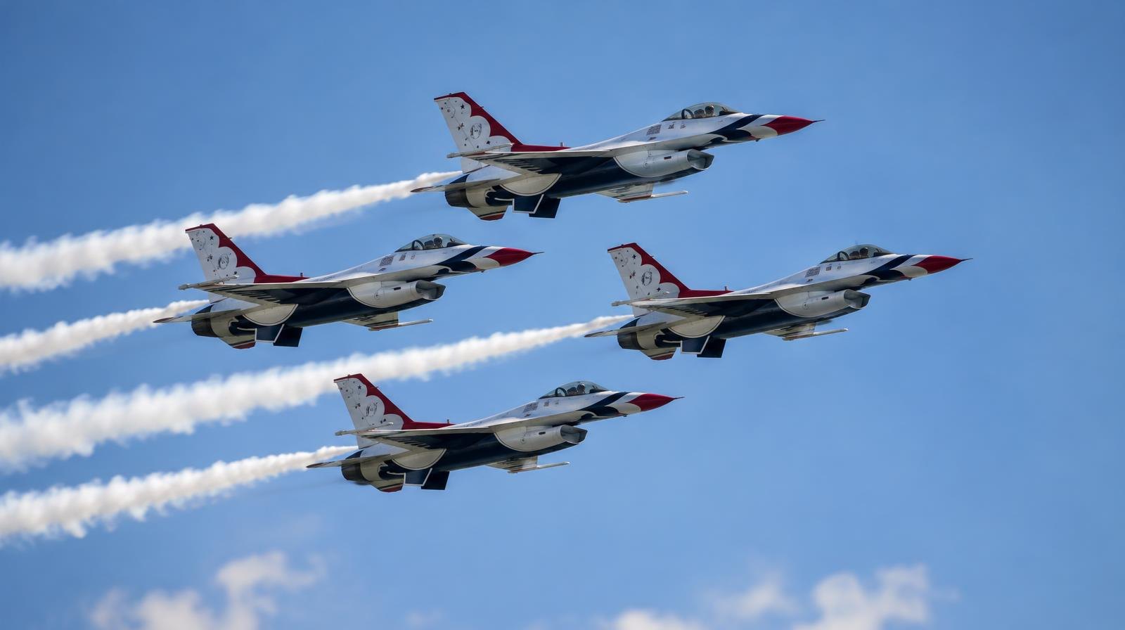 Several military jets flying in close diamond formation with white smoke trails against blue sky