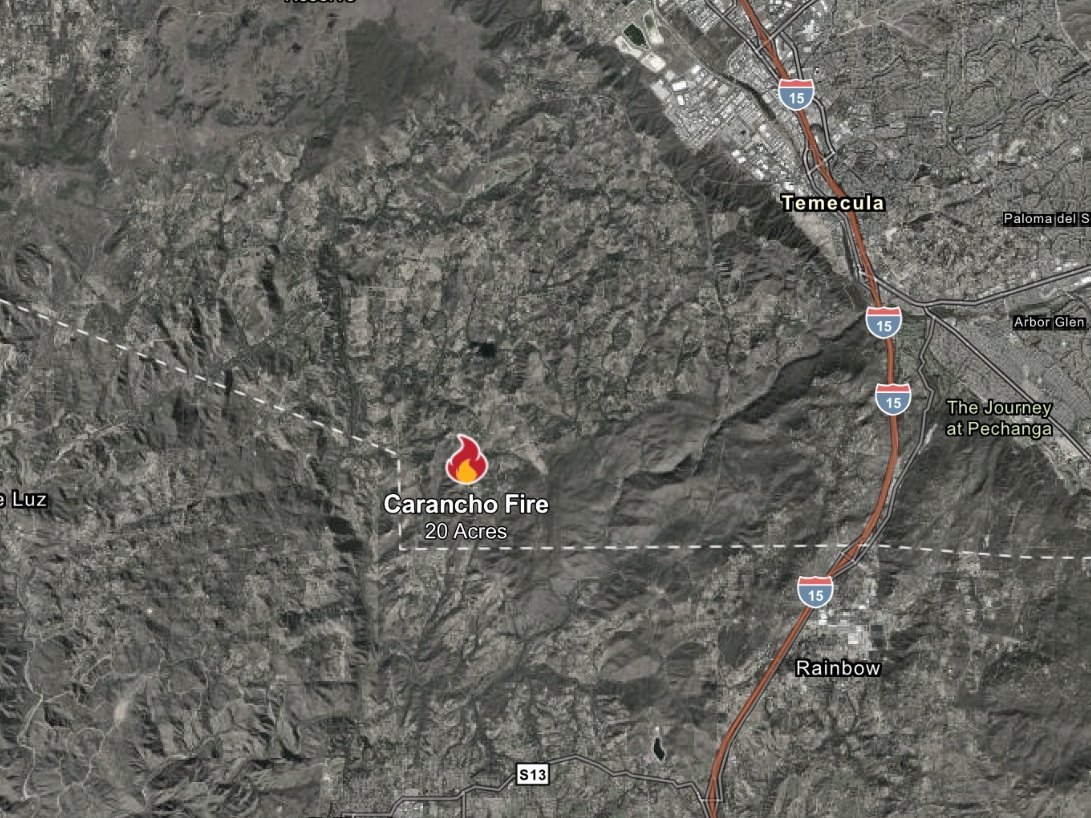 Satellite map with a fire icon marking a wildfire location west of a city near a highway.