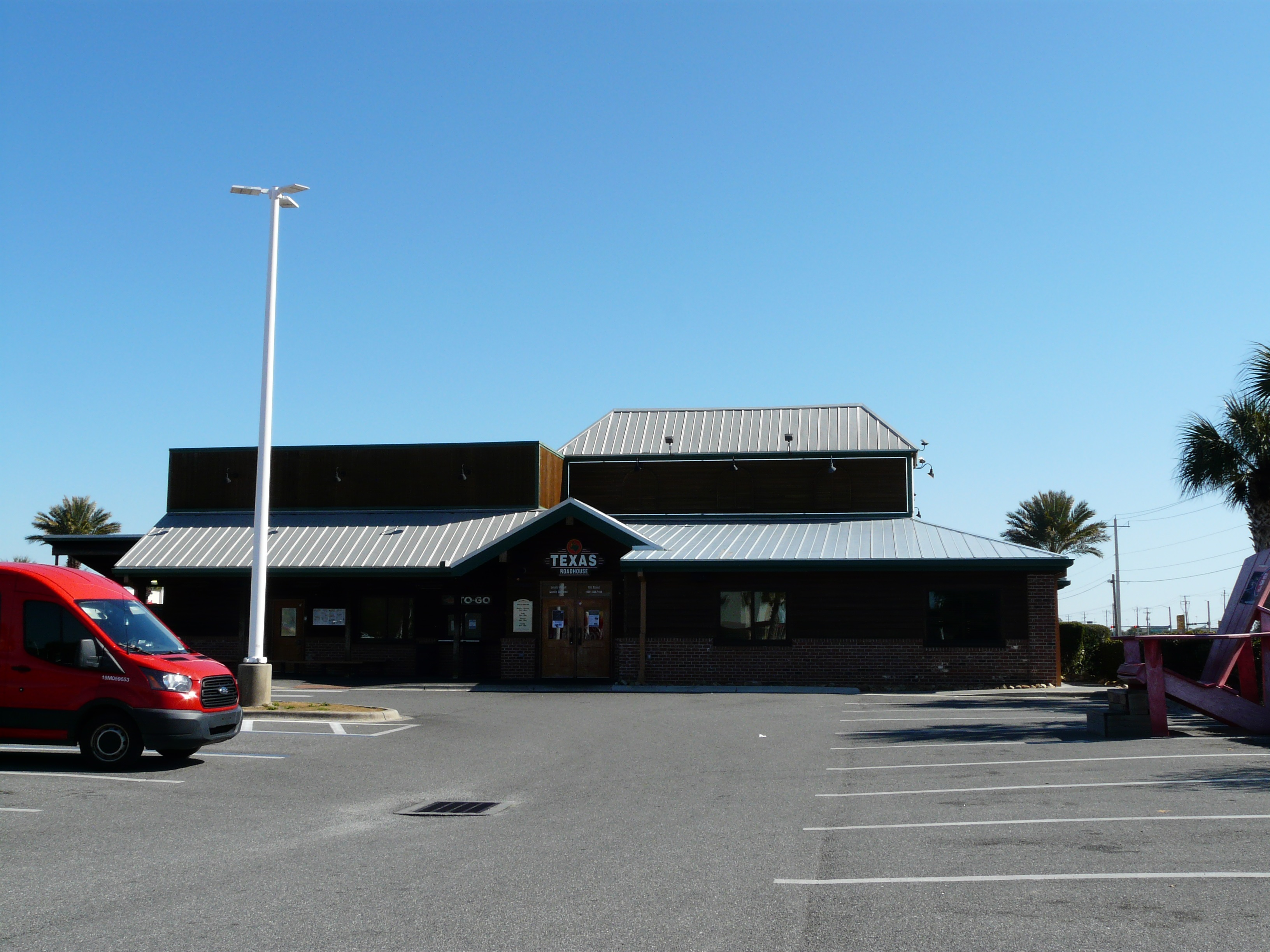 Exterior of a Texas Roadhouse restaurant with dark wood facade and metal roof.