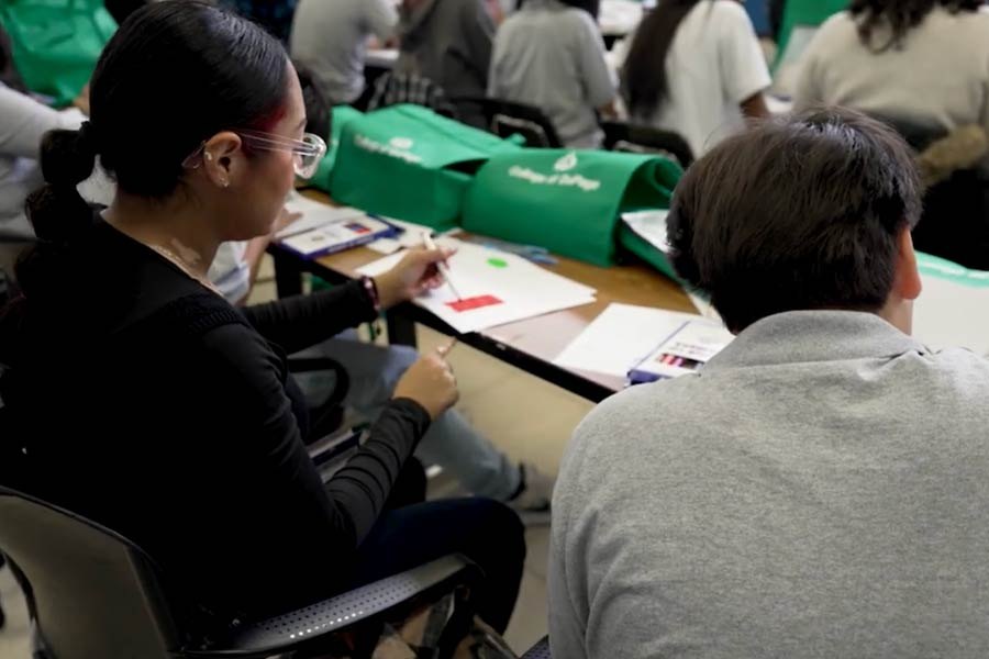 Two students seated at a table reviewing papers, with College of DuPage tote bags visible nearby.