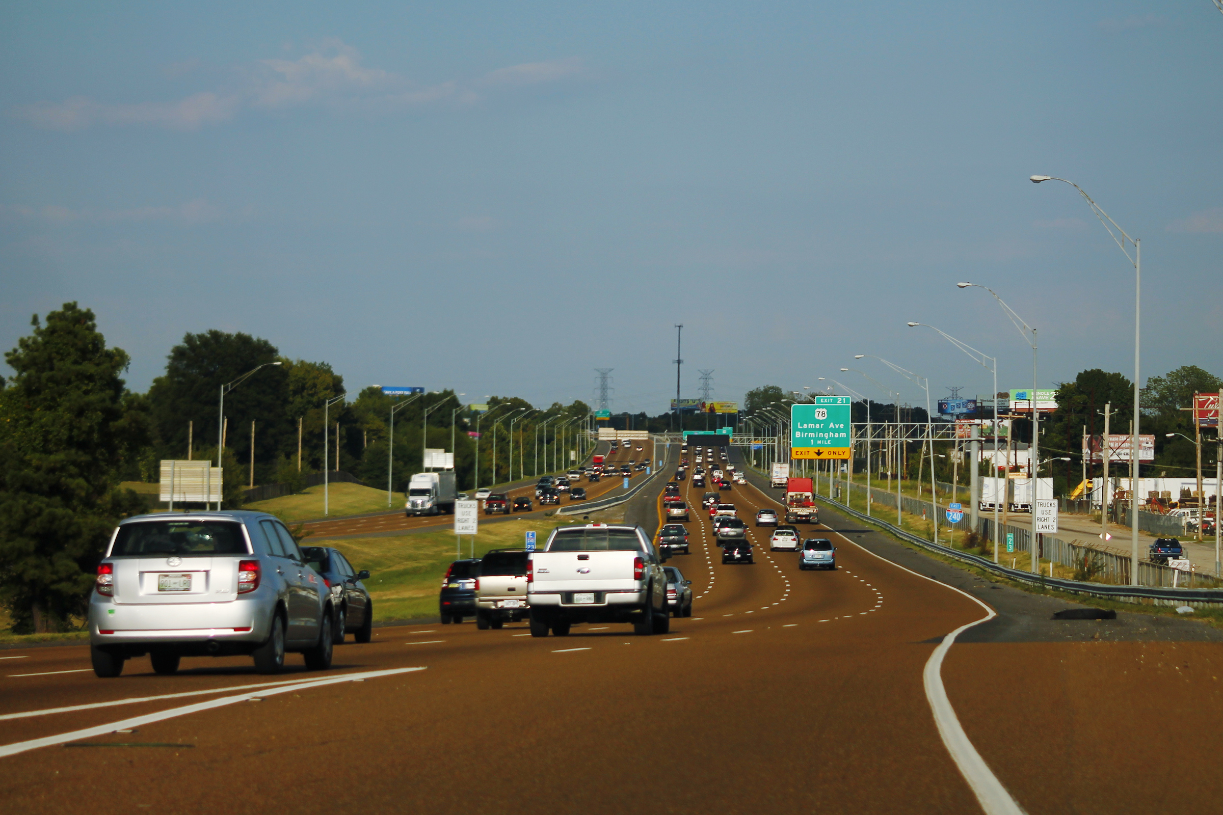 A busy multi-lane divided highway with traffic under a partly cloudy sky.