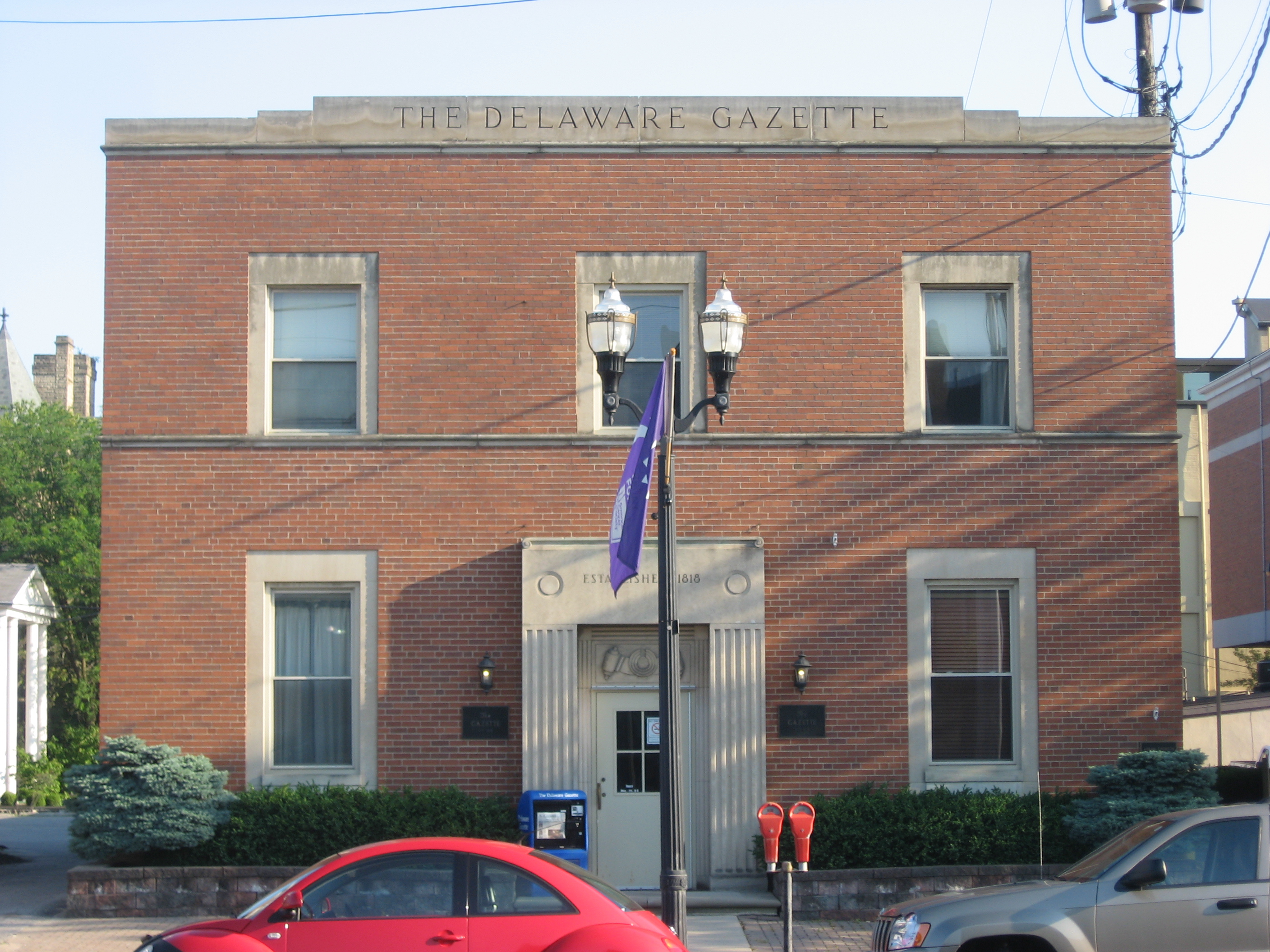 Two-story red brick building with 'The Delaware Gazette' inscribed on the facade.