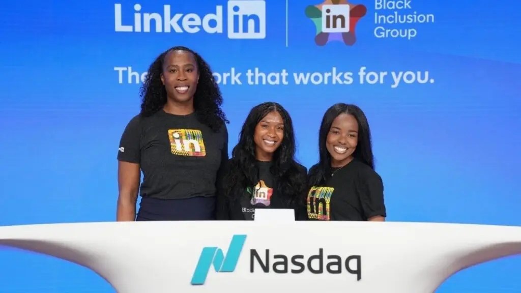 Three women in matching black t-shirts standing behind the Nasdaq podium with LinkedIn branding displayed behind them.