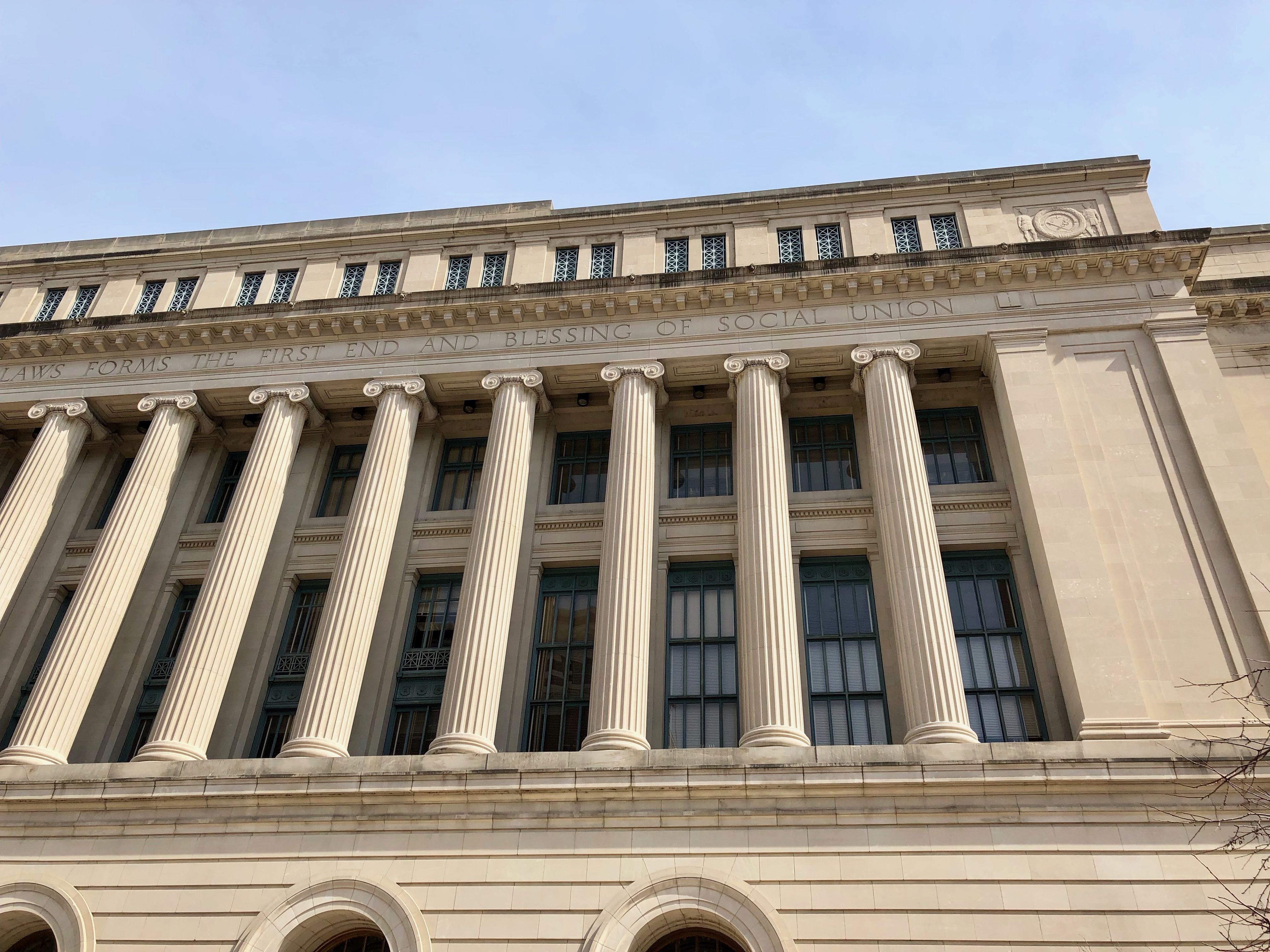 Low-angle view of tall Ionic columns on the limestone facade of a neoclassical courthouse.