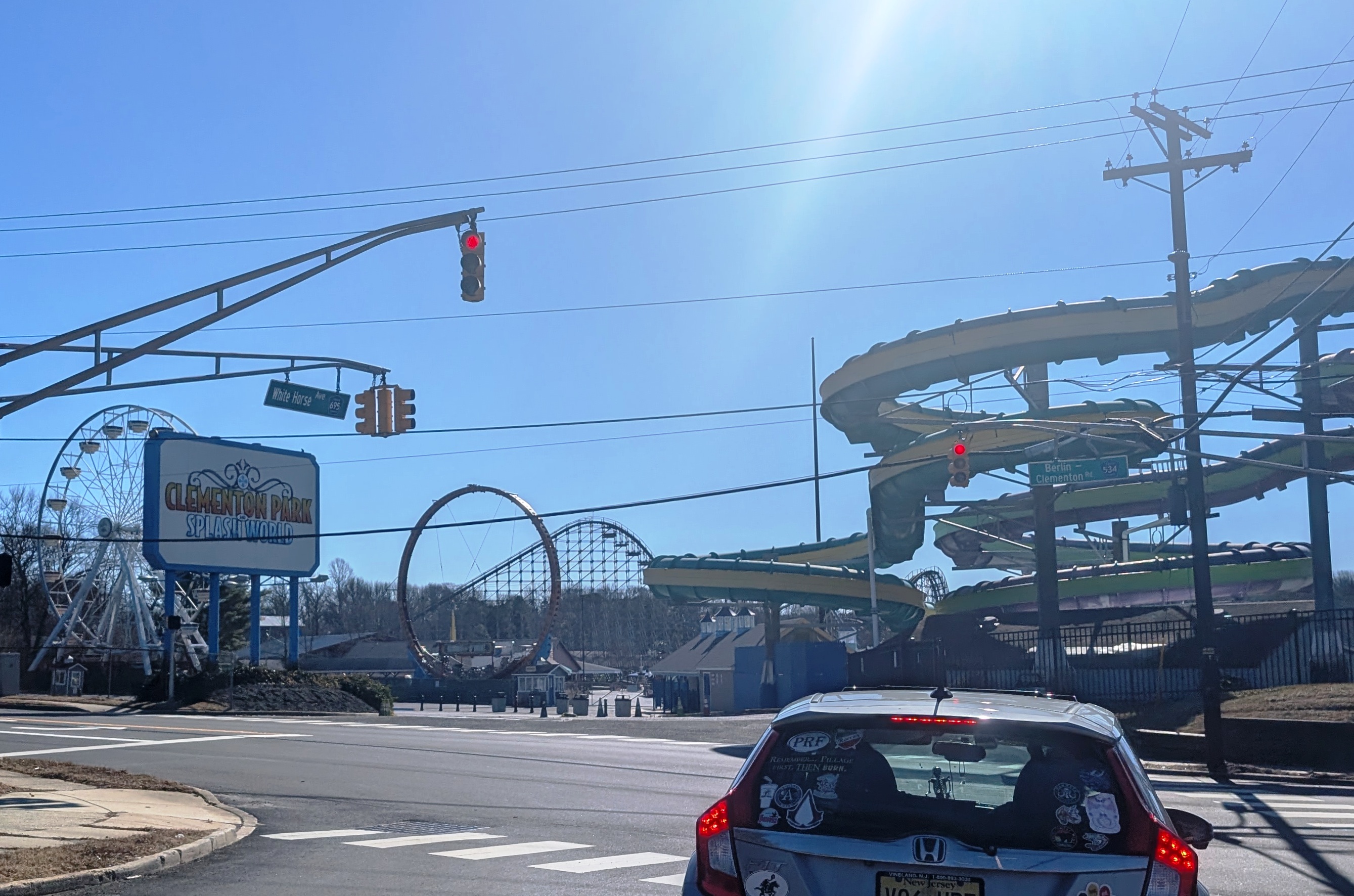 Amusement park entrance sign and rides visible from a street intersection.