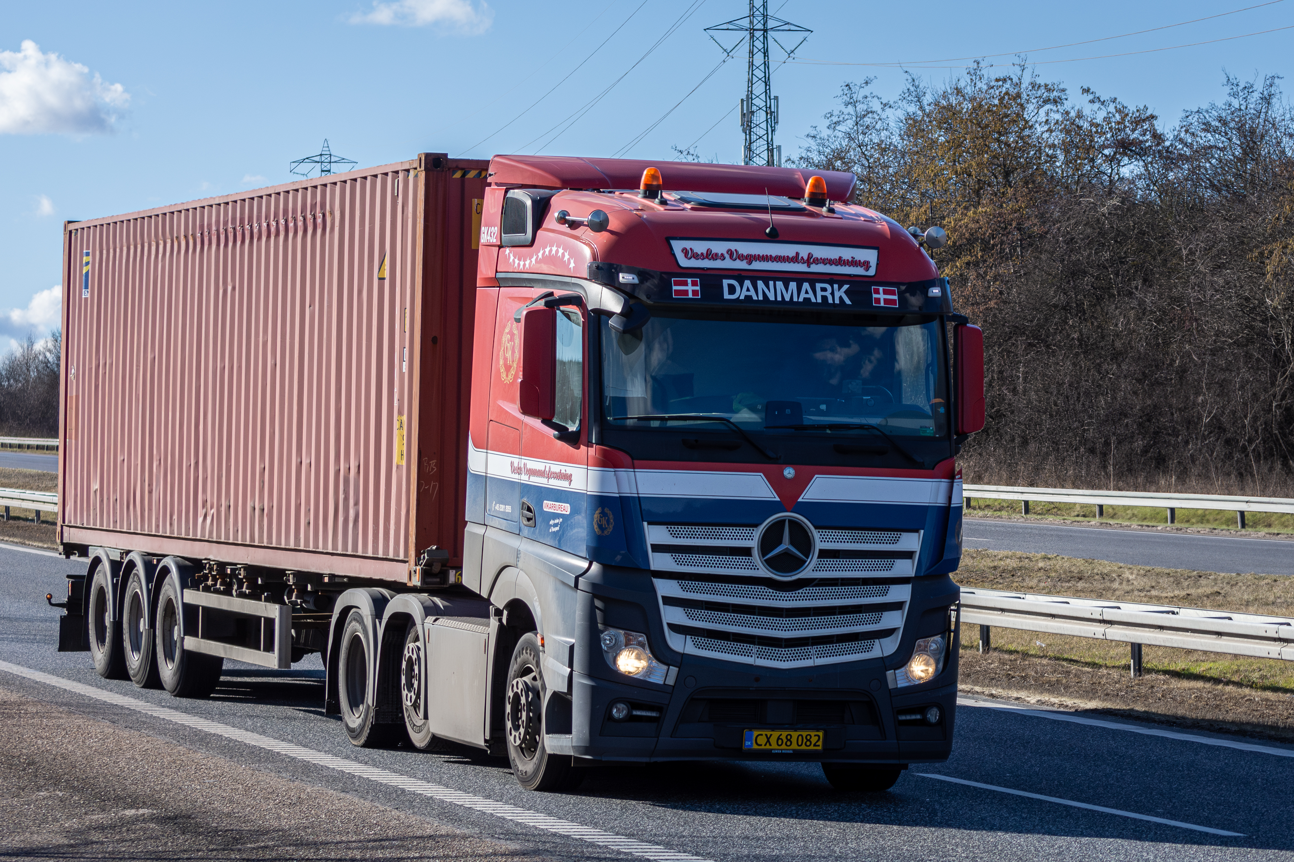 A large semi-truck pulling a shipping container along a highway.