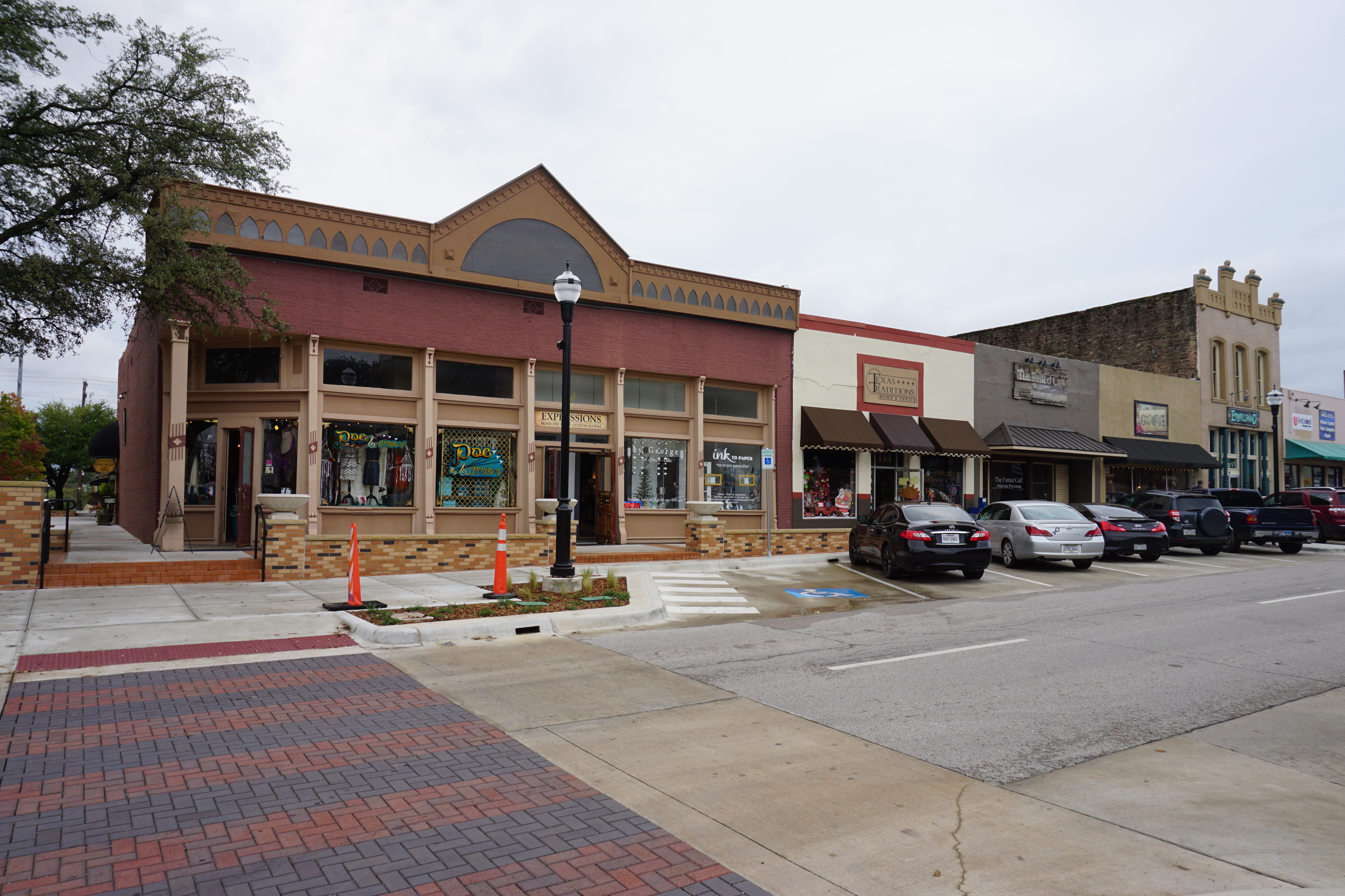 Commercial storefronts and parked vehicles along a small-town street on an overcast day.