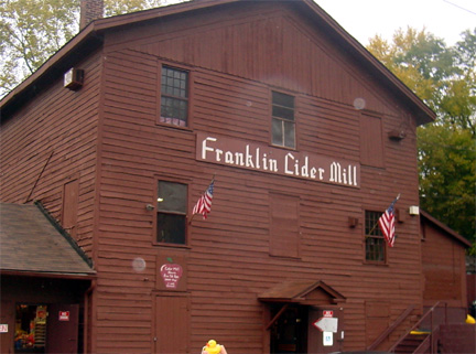 Red wooden barn building with a painted Franklin Cider Mill sign above the entrance.