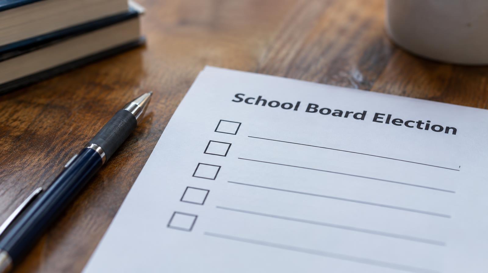 A paper ballot with candidate name slots and empty checkboxes beside a pen.