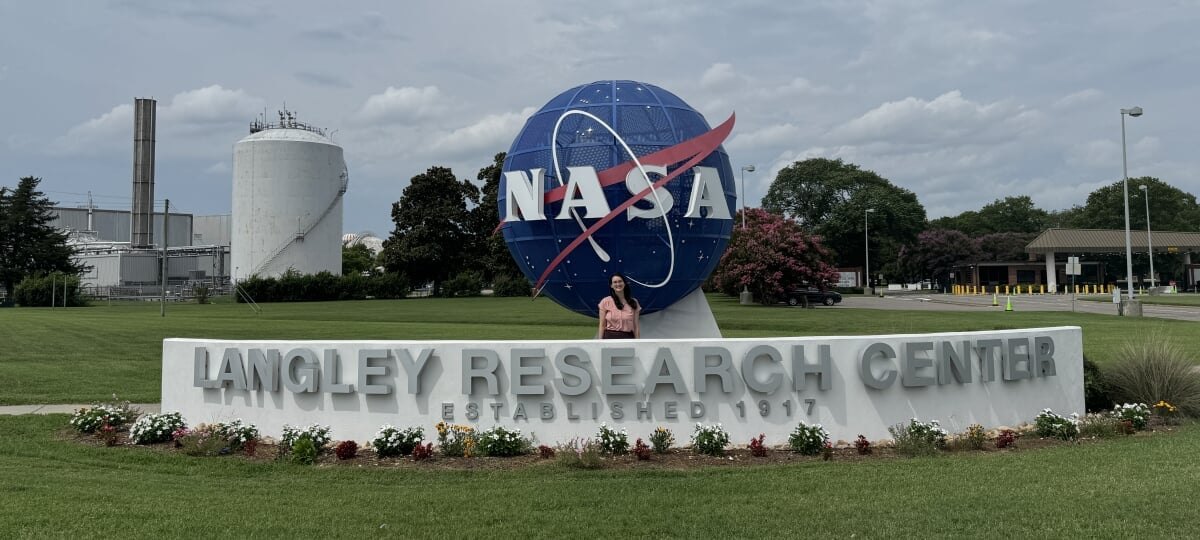 Person standing in front of a large NASA Langley Research Center entrance sign outdoors.