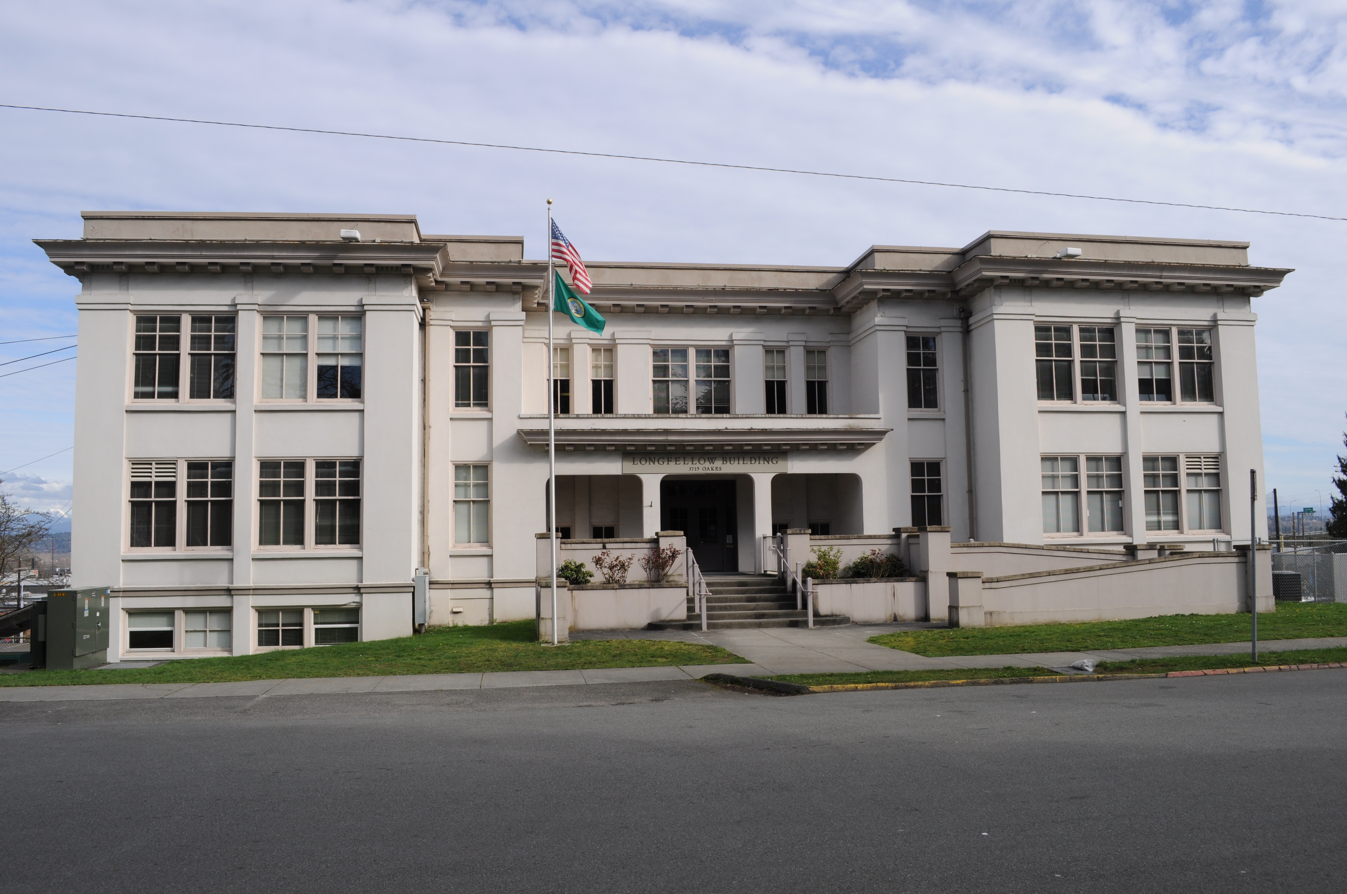 Neoclassical two-story white building with US and Washington State flags on a flagpole out front.