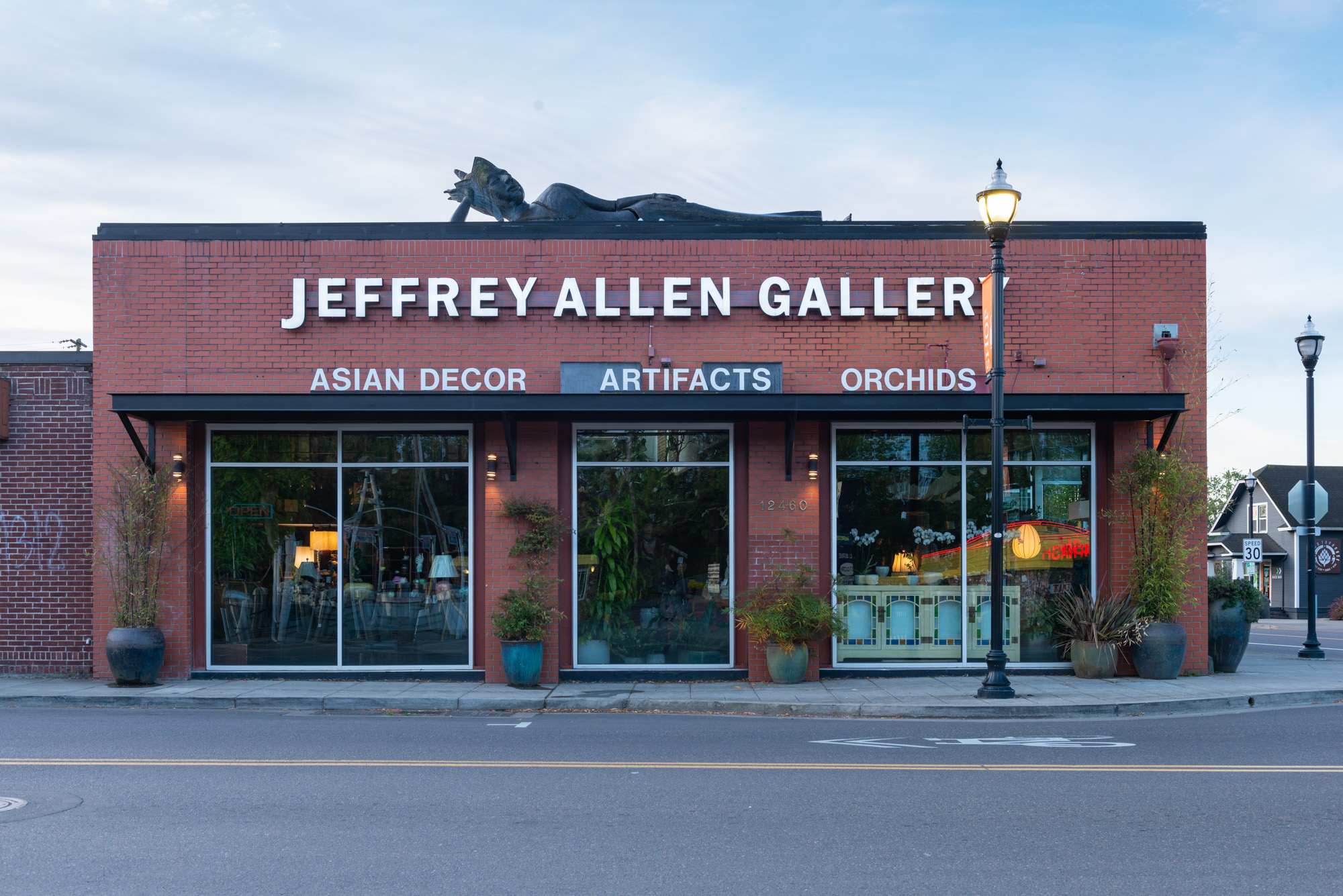 Red-brick storefront with large windows and a decorative sculpture on the roofline.