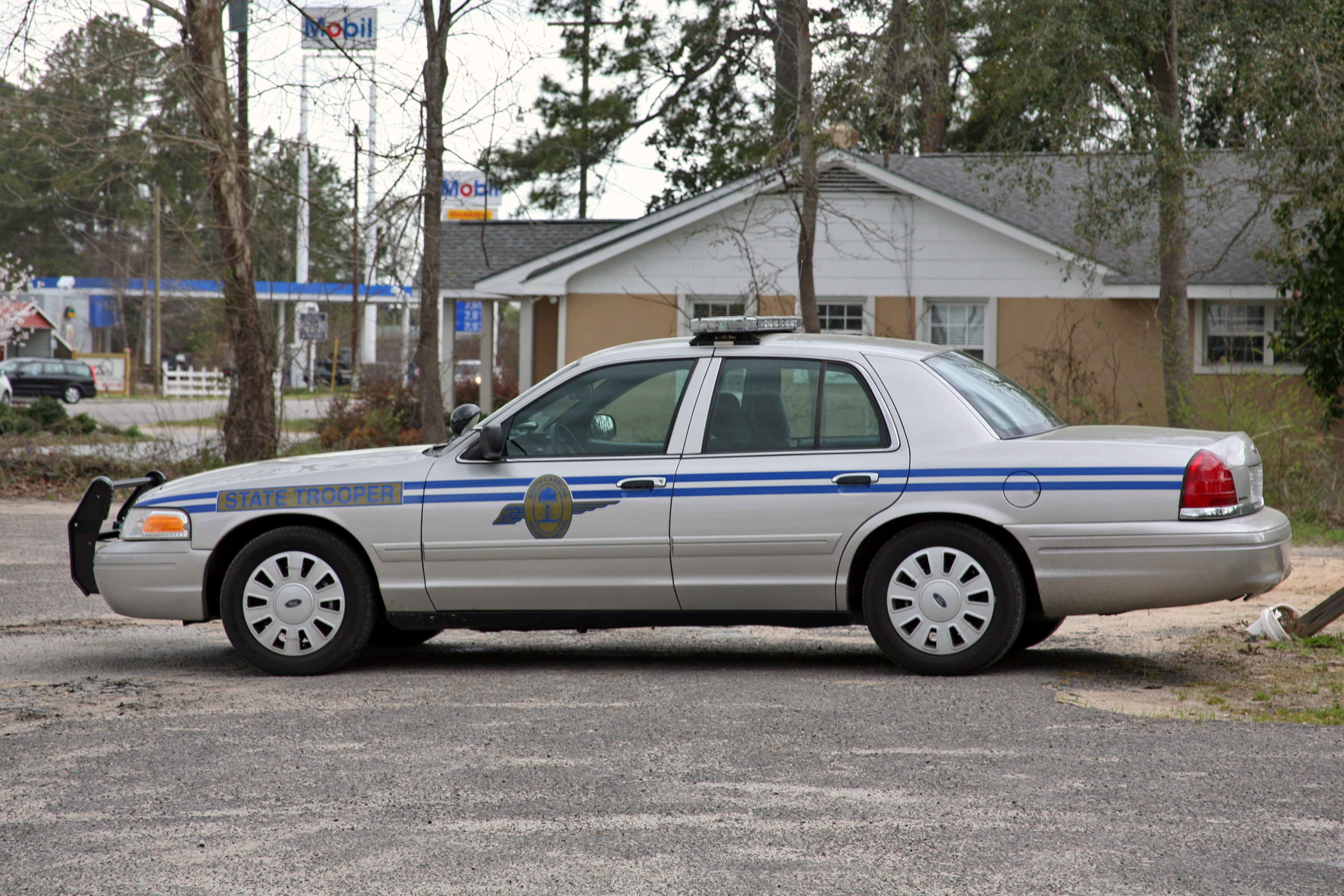A highway patrol car with blue stripe livery and roof-mounted light bar parked outdoors.