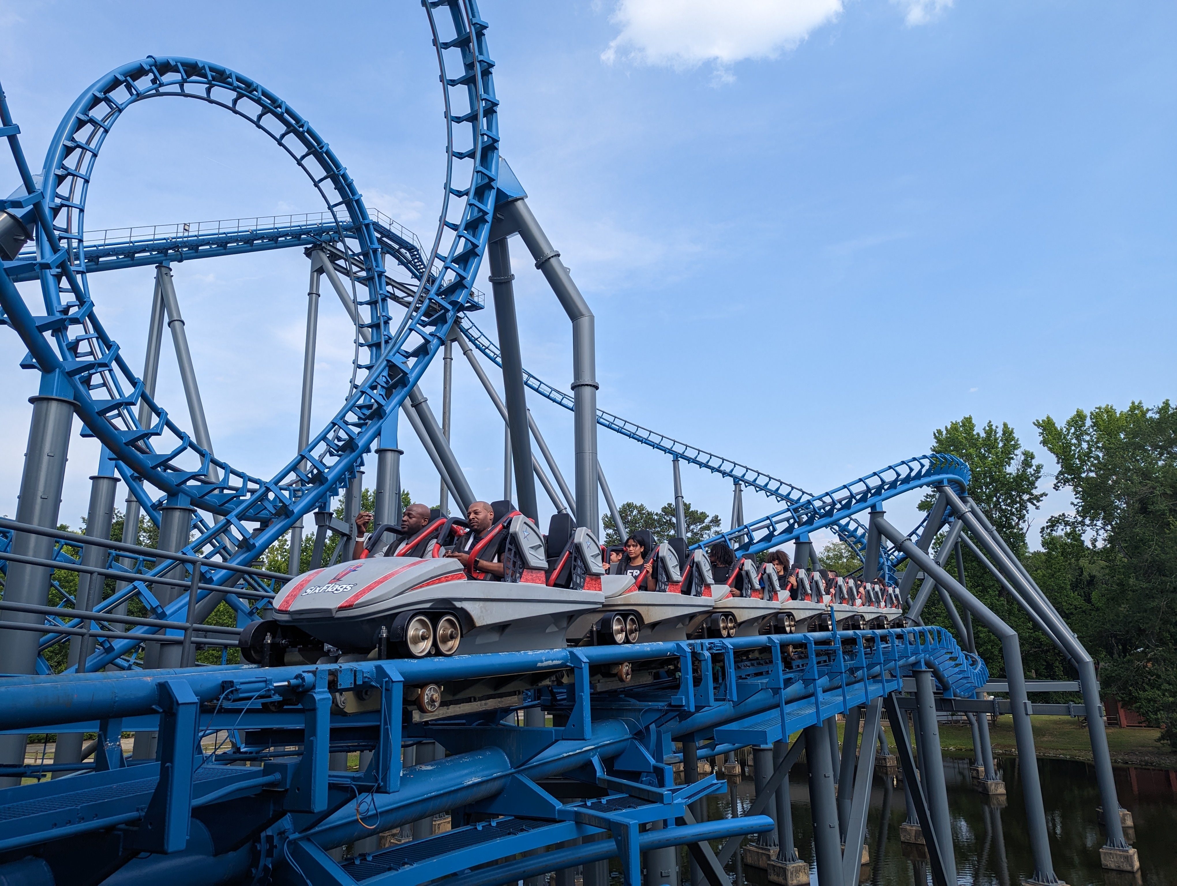 Roller coaster train with riders on a blue steel track, loop in background.