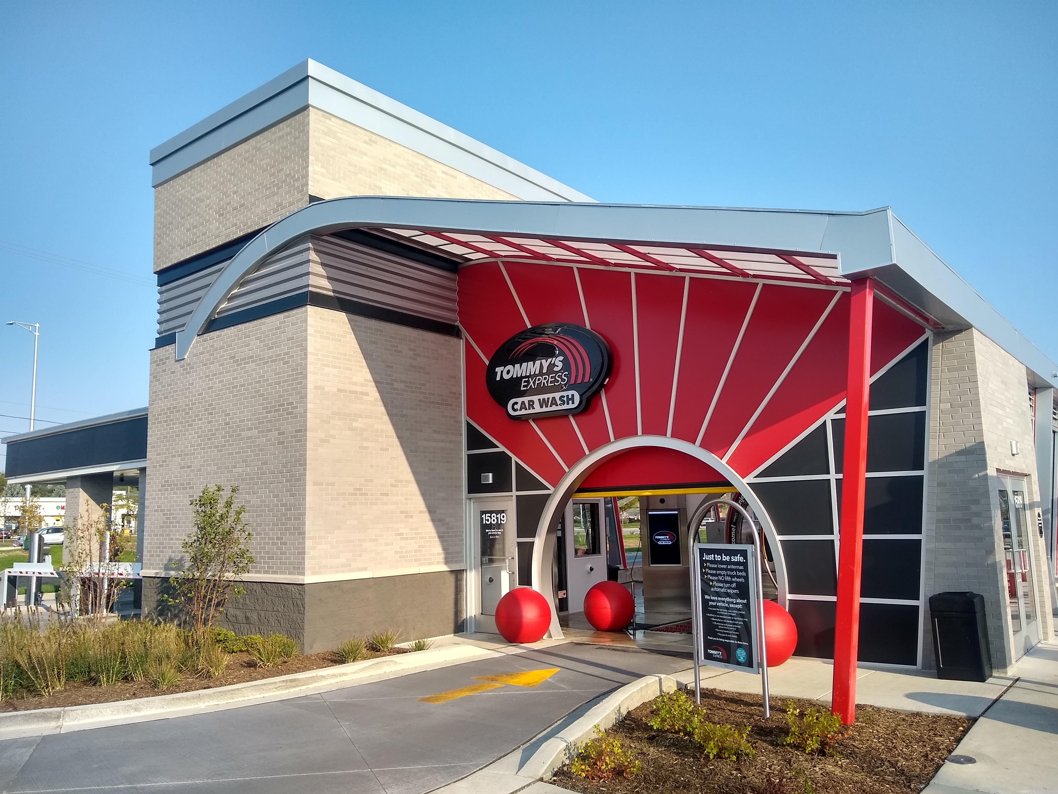Entrance to an express tunnel car wash with a red canopy and arched tunnel opening.