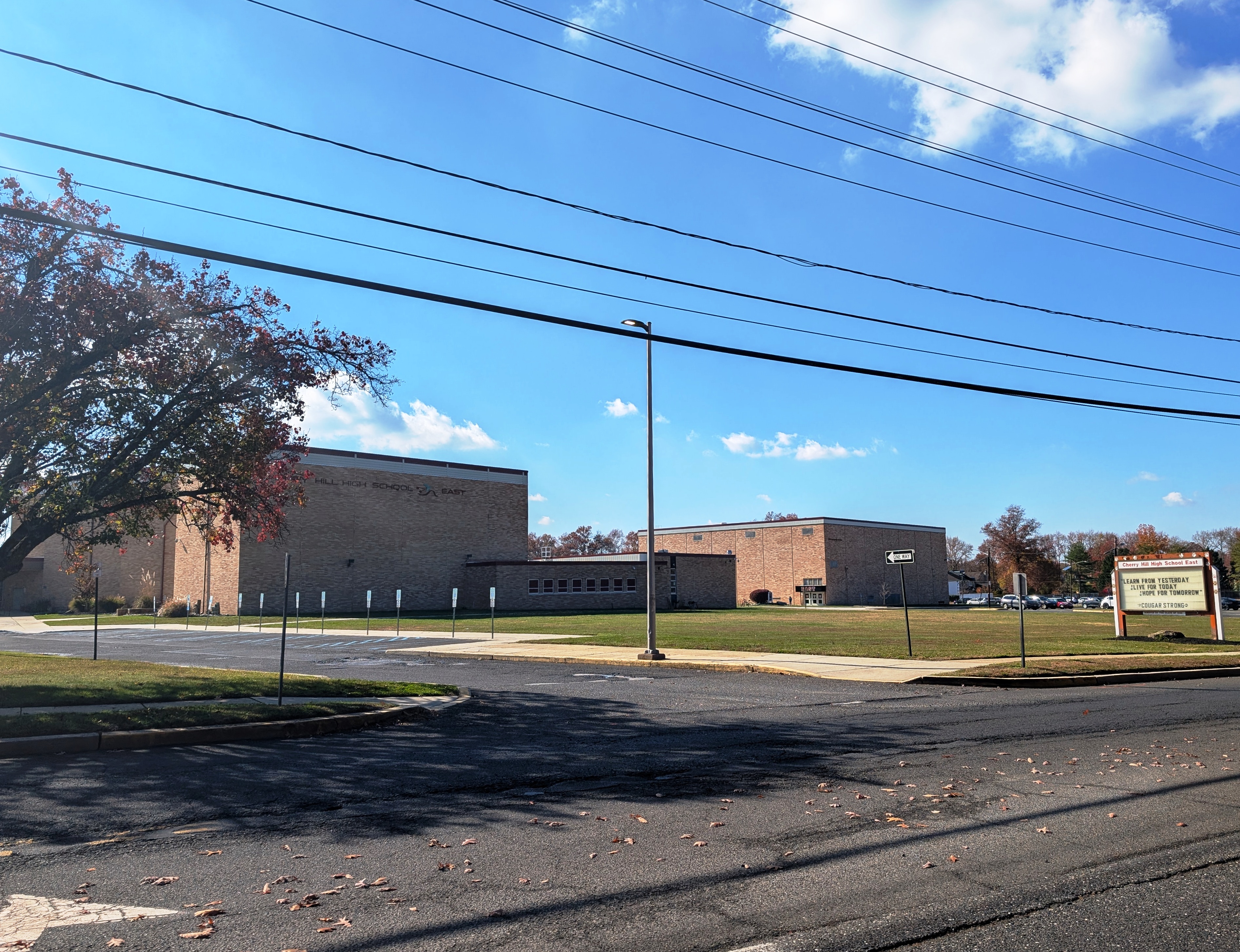 Brick exterior of a large high school building with a marquee sign and autumn trees.