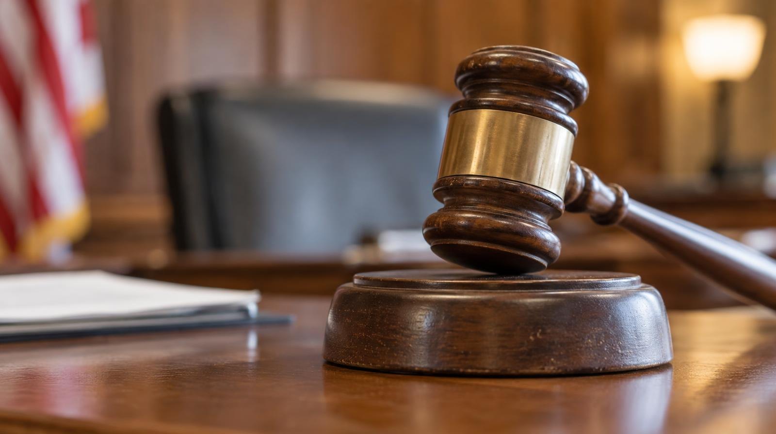 Wooden gavel resting on its sound block on a wooden surface.