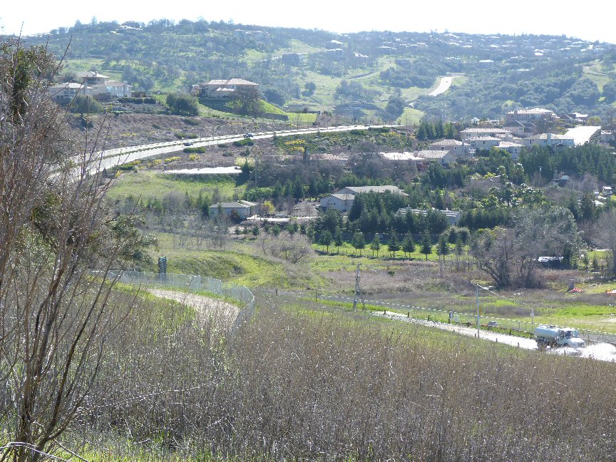 Hillside suburban neighborhood with winding roads, homes, and green vegetation.