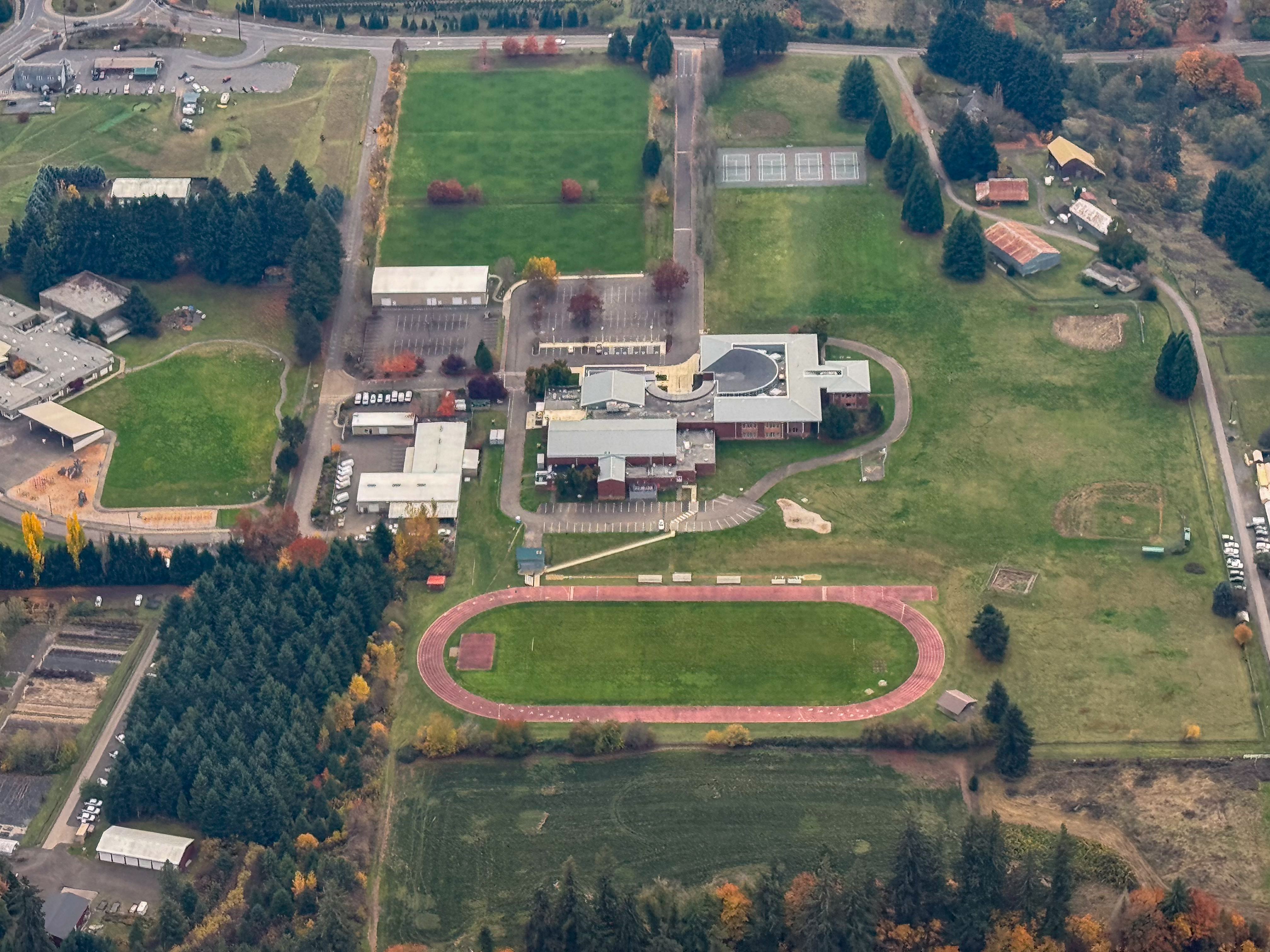 Aerial view of a school campus with athletic fields and surrounding roads in a suburban area.