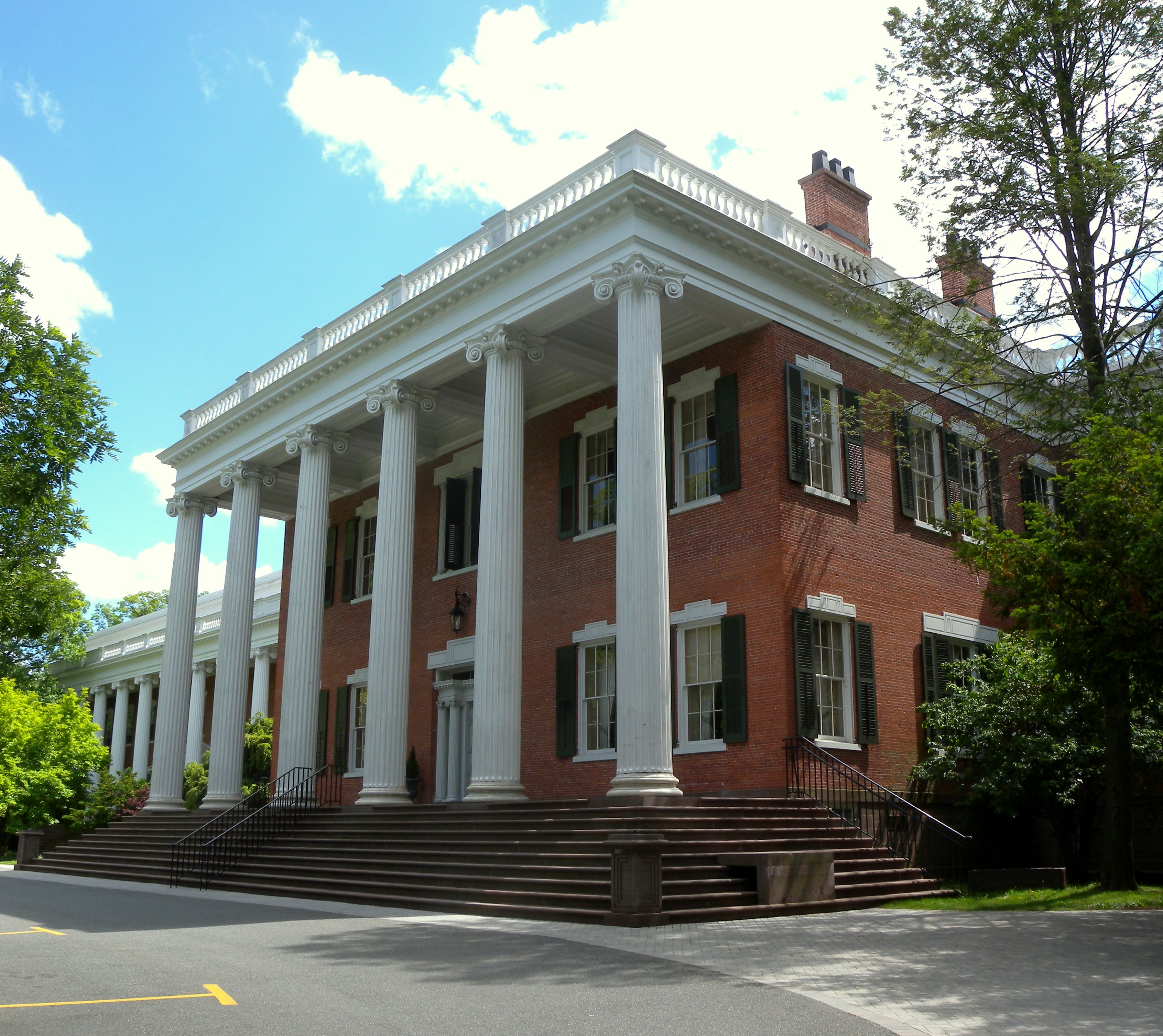 Red brick Greek Revival building with tall white columns on a university campus.