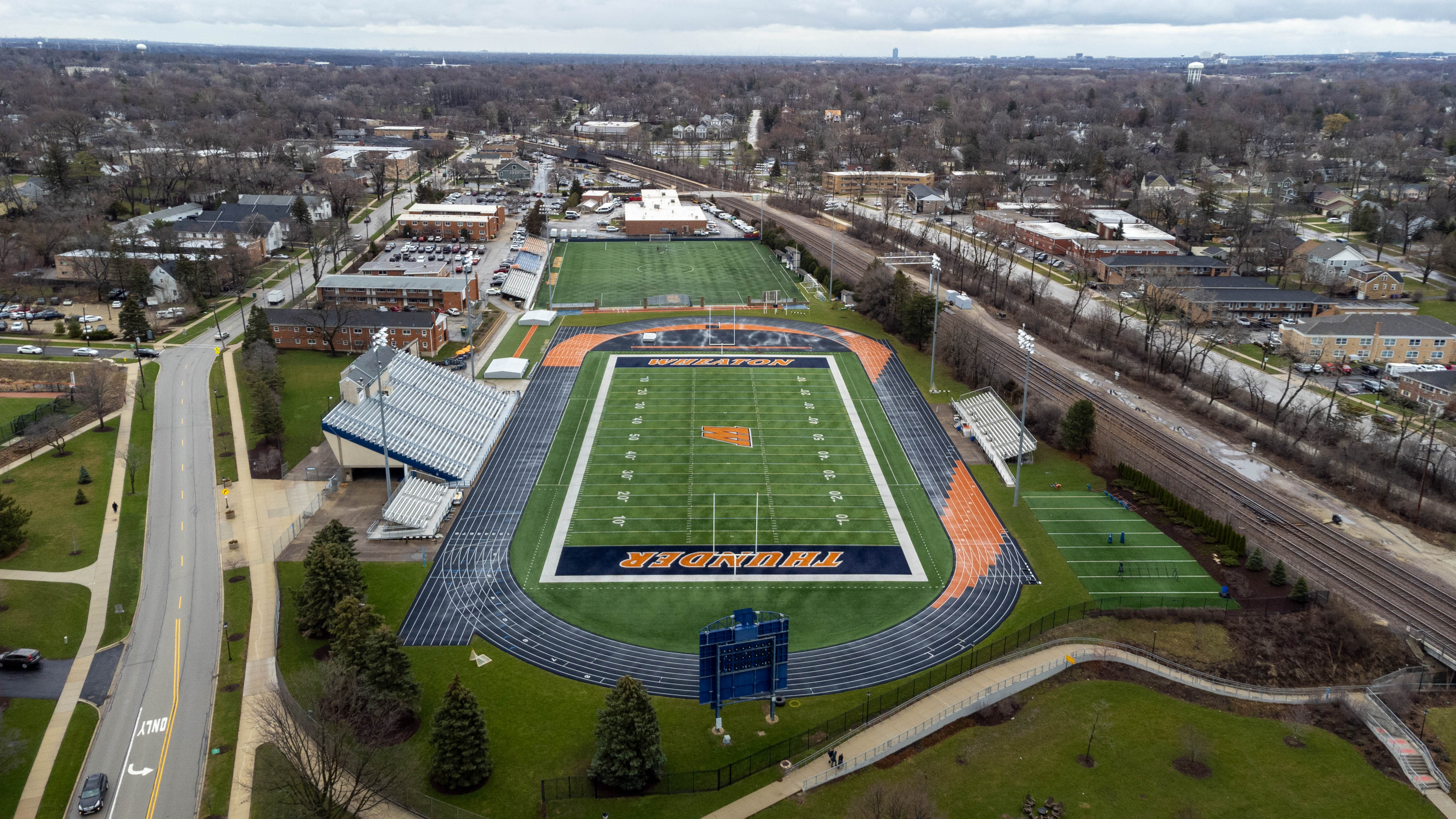 Aerial view of a college football stadium with blue track and orange end zones reading THUNDER.