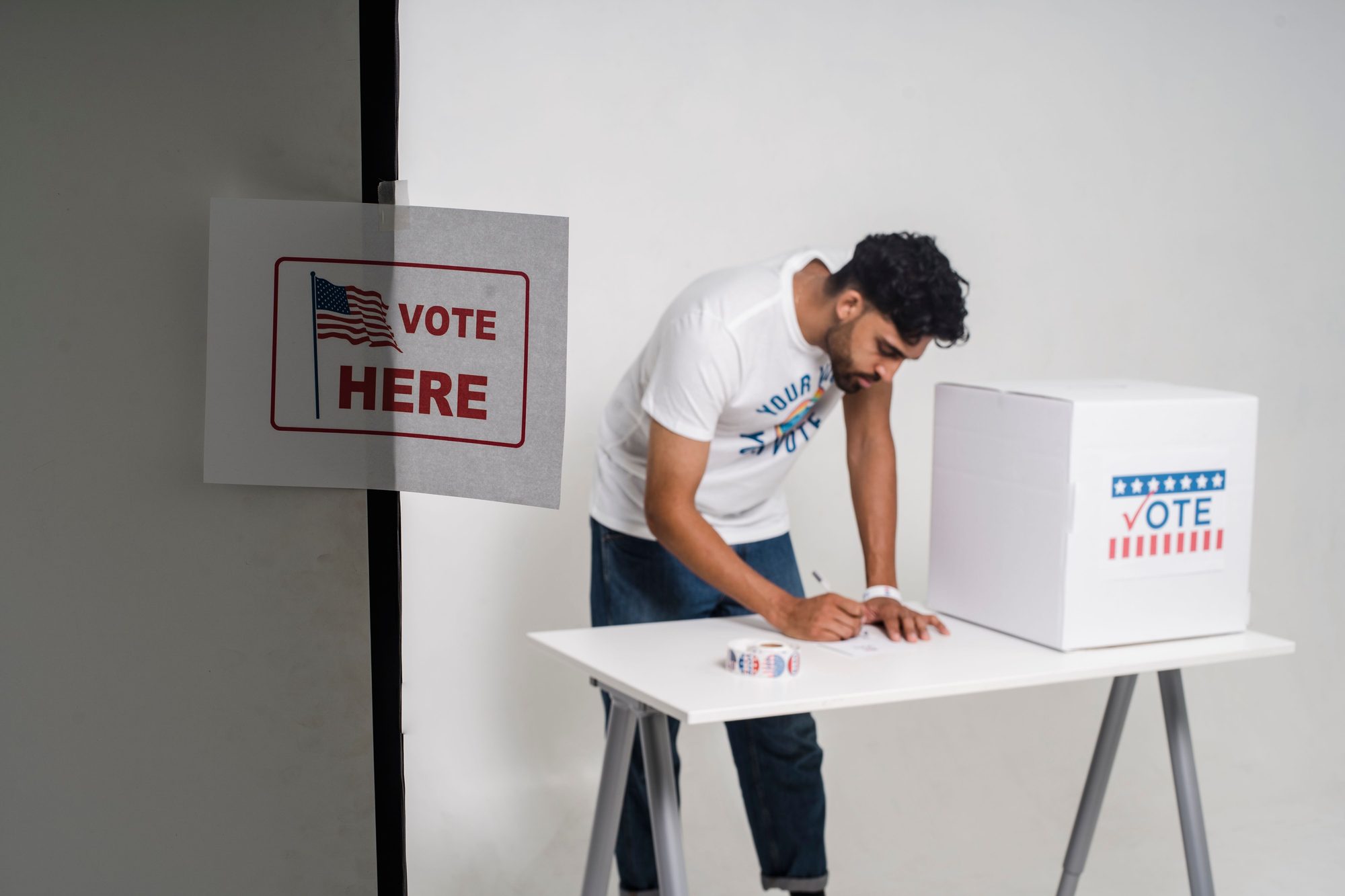A man casting his vote in a ballot box, highlighting the democratic process in a studio setting.