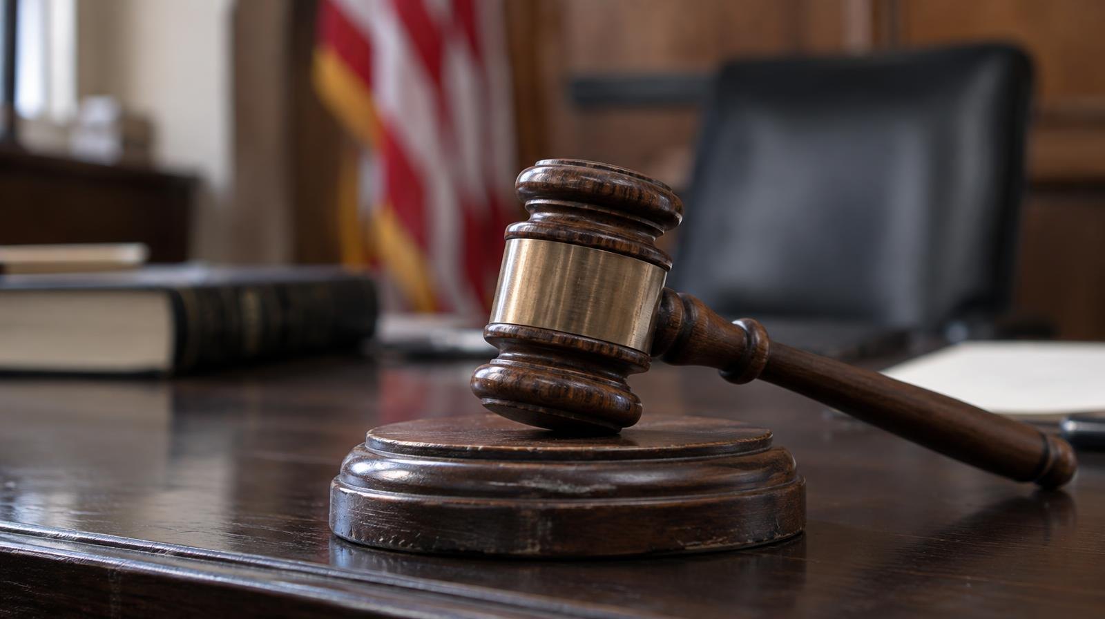 A wooden gavel resting on its sound block on a dark surface.
