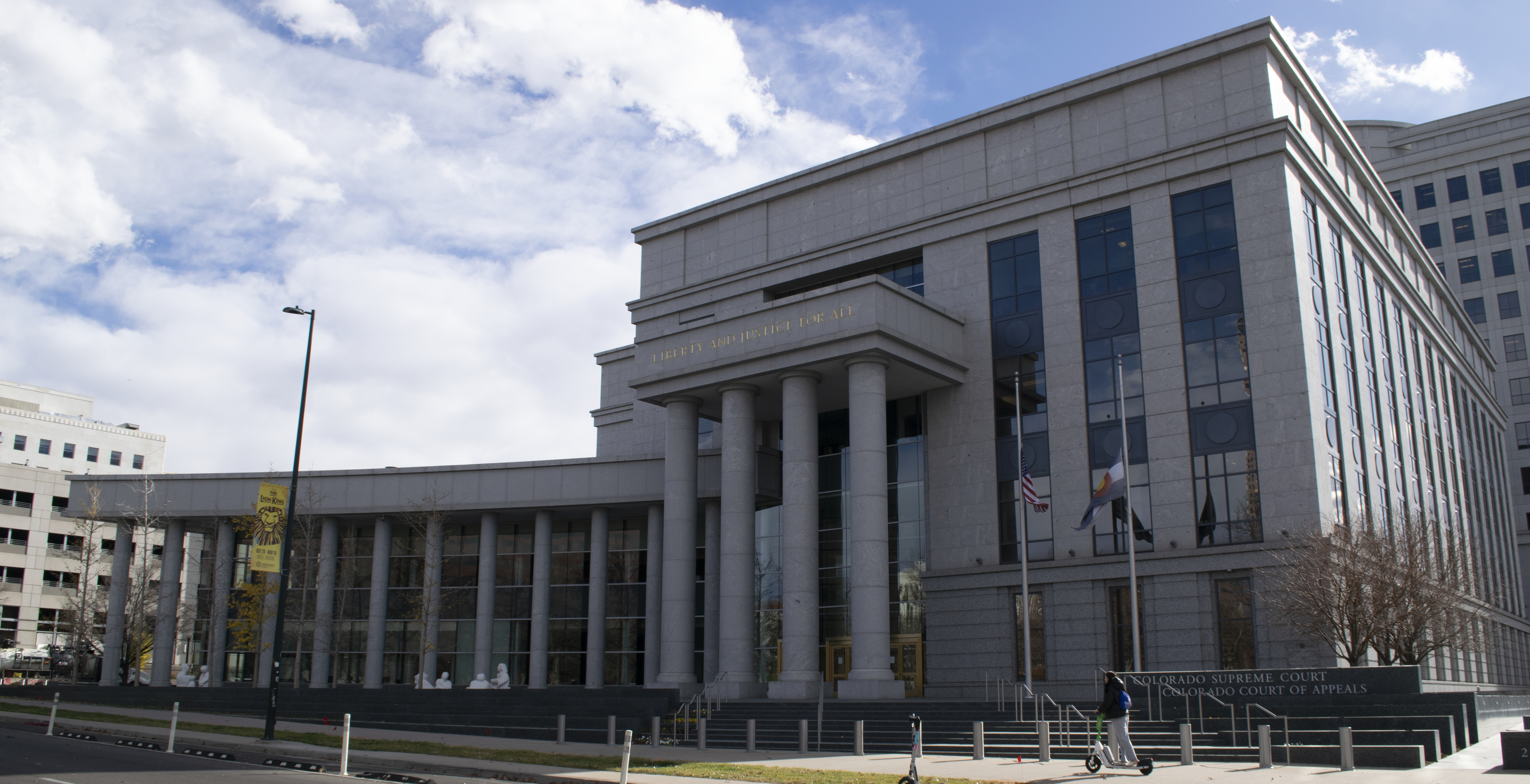 Neoclassical stone courthouse with tall columns and American and state flags.