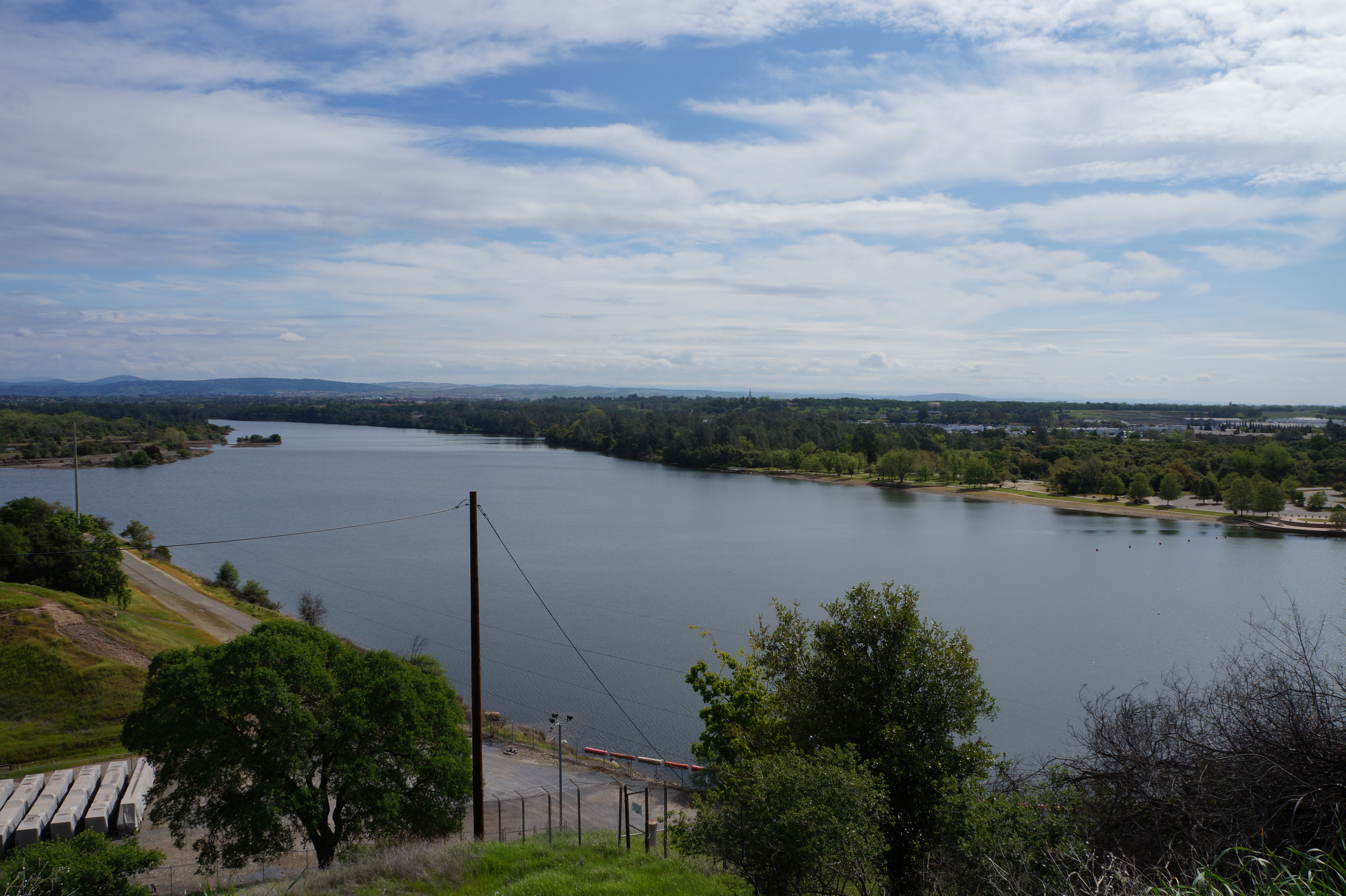 Wide lake view with tree-lined shores under a partly cloudy sky.