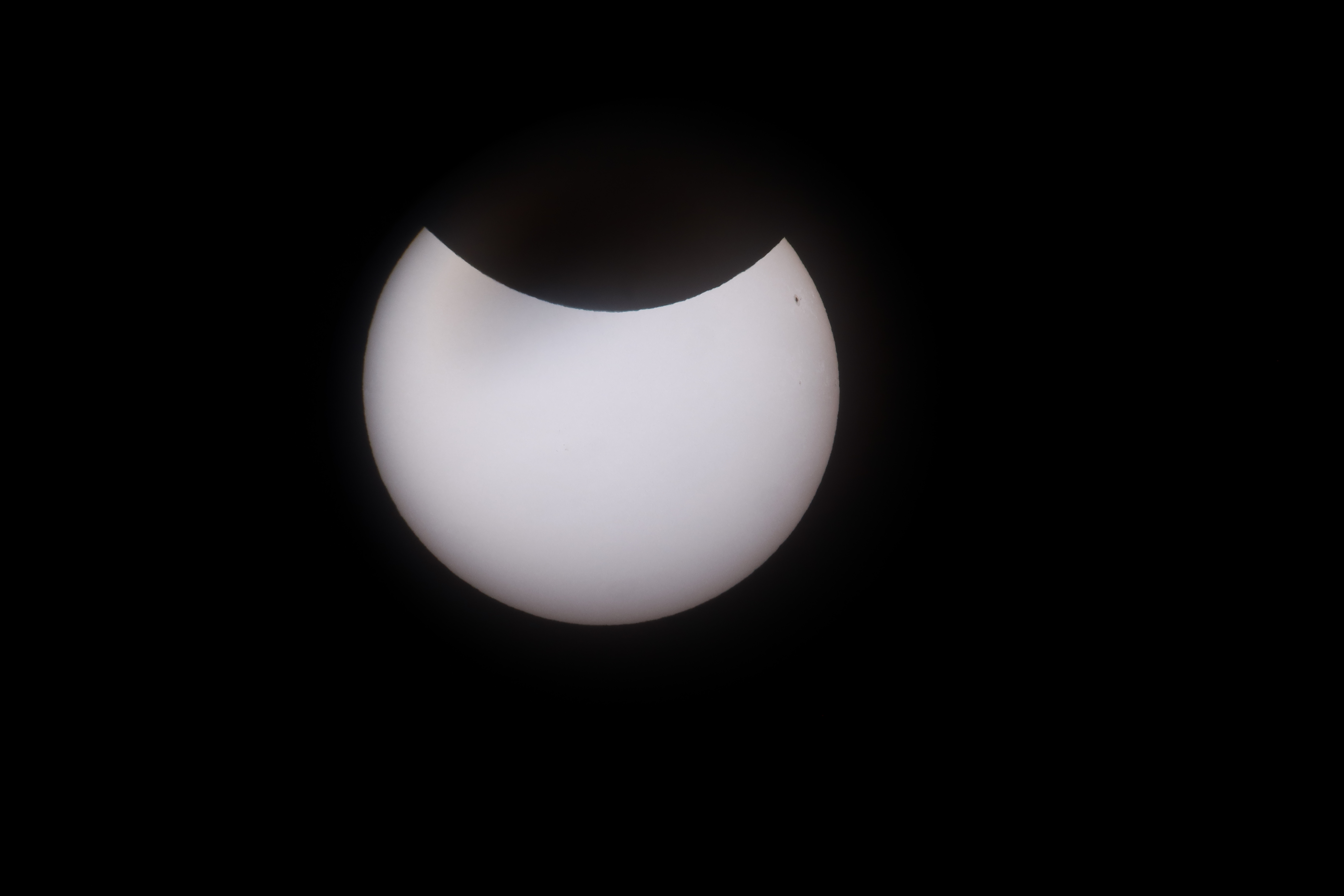 The moon covers most of the sun, leaving a bright white crescent against a black sky.