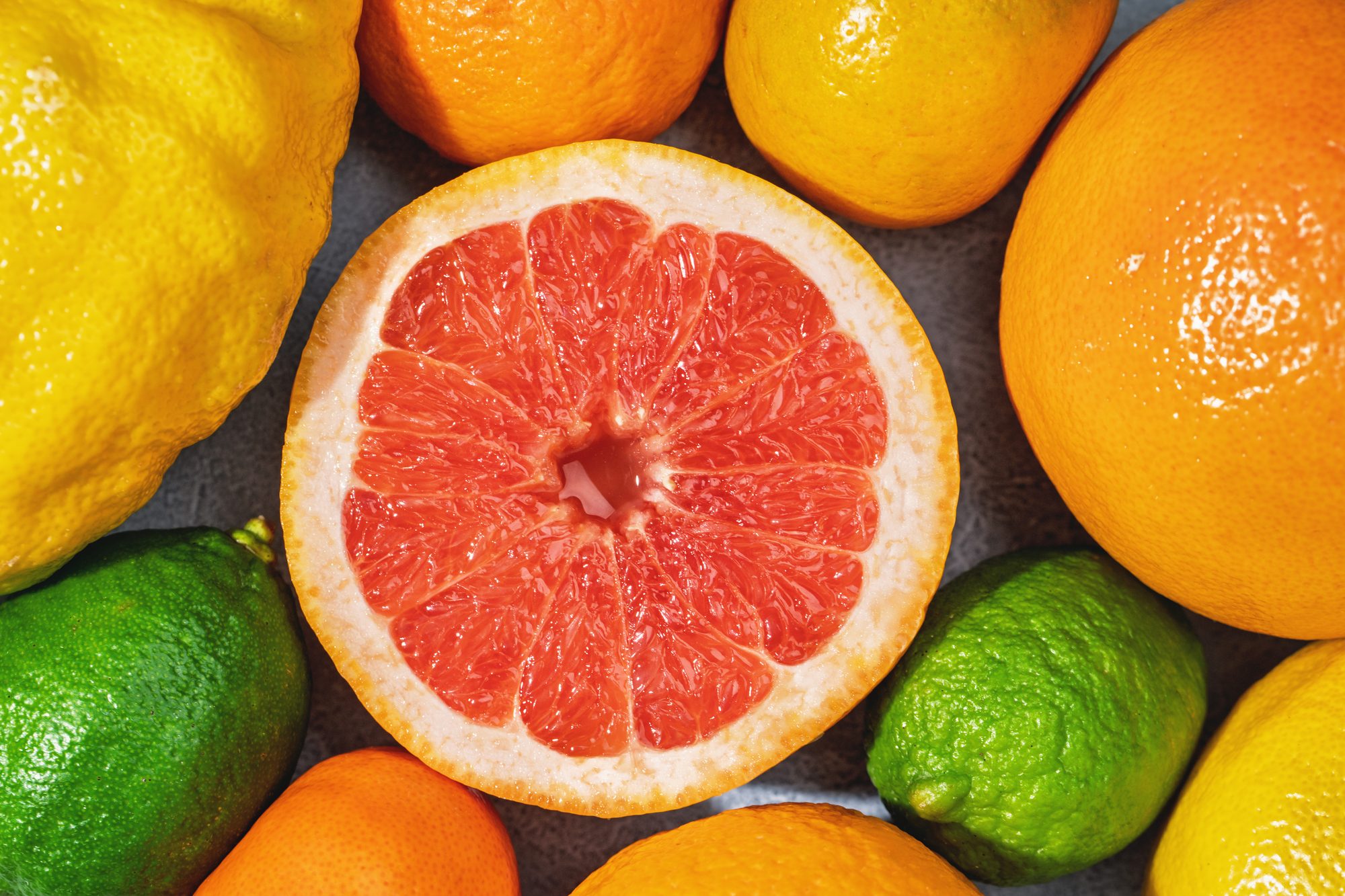 Close-up fo pink grapefruit pulp and assorted citrus fruit around it. Flat lay summer vibe