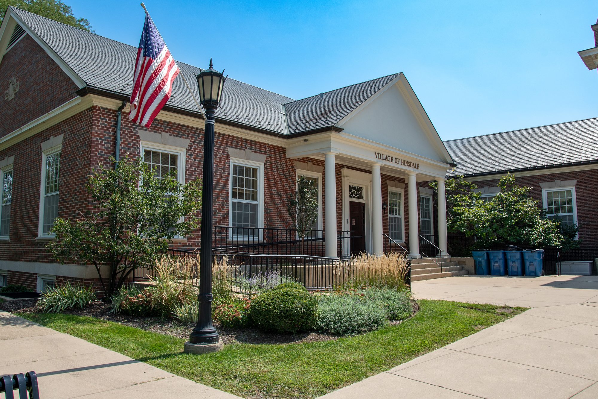 Brick municipal building with white columns and American flag out front